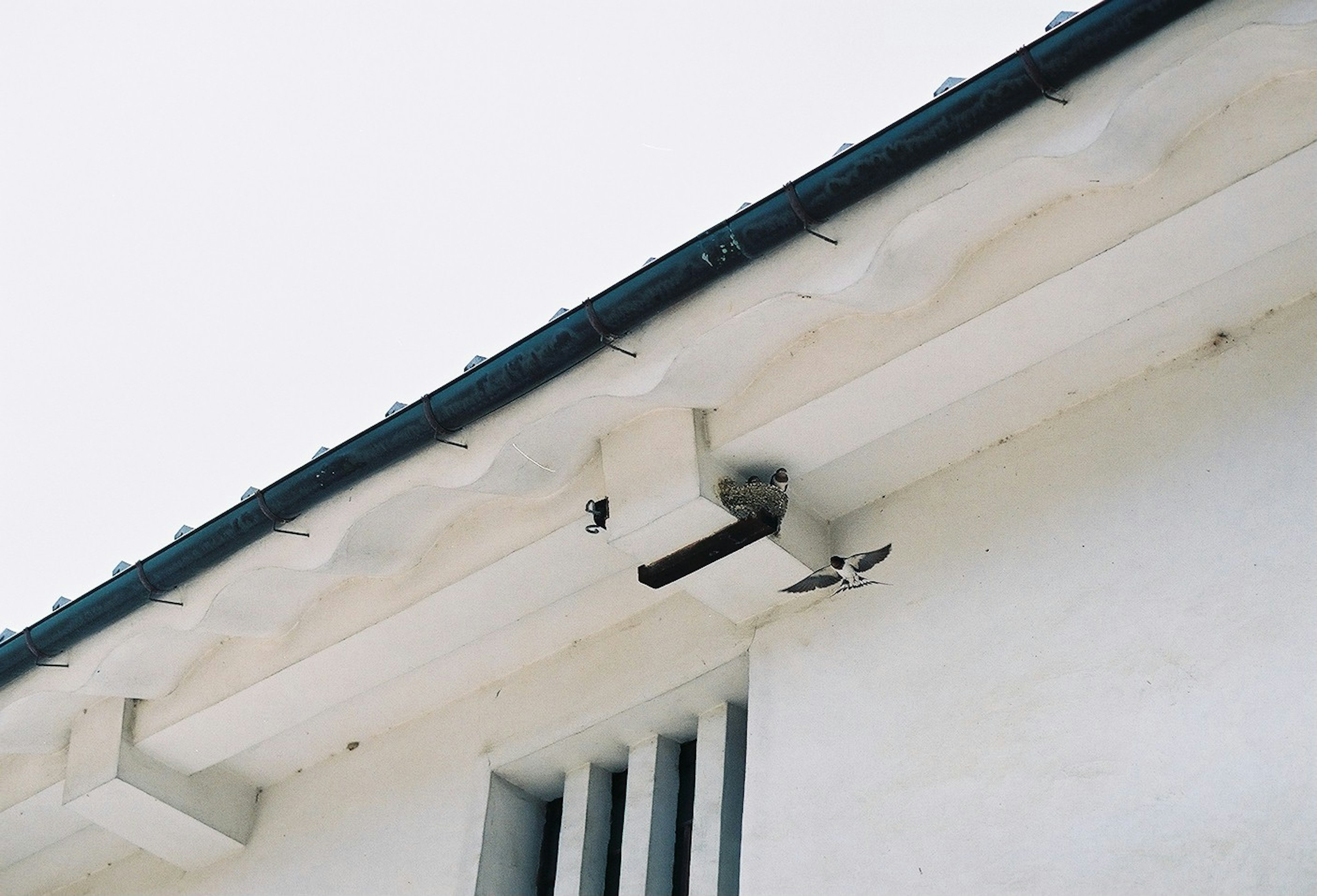 Cámara de vigilancia y rejilla de ventilación debajo del techo de un edificio blanco