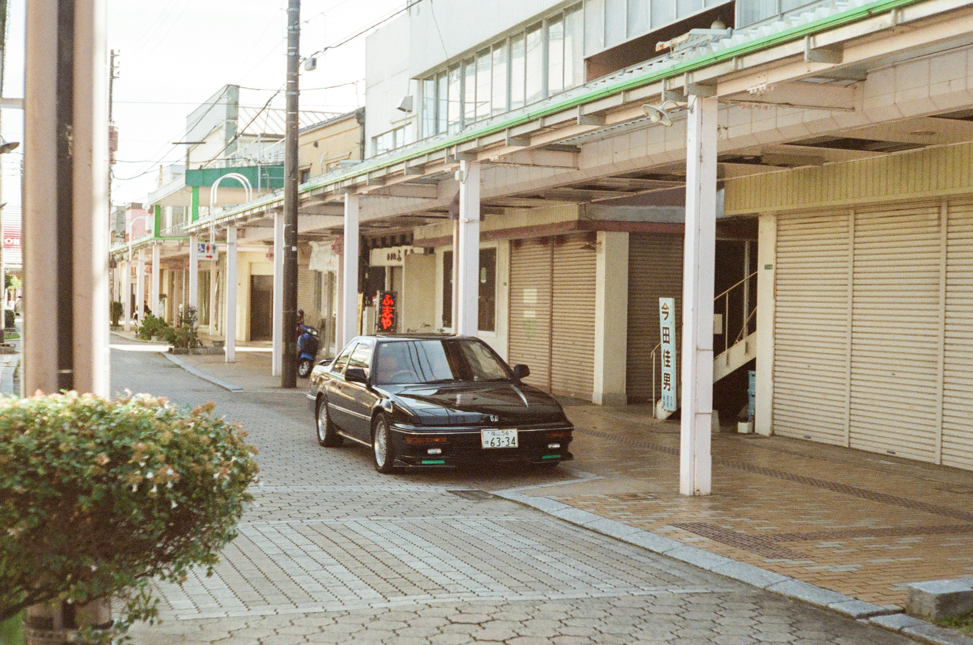 黒い車が静かな通りに停まっている古い商店街の風景