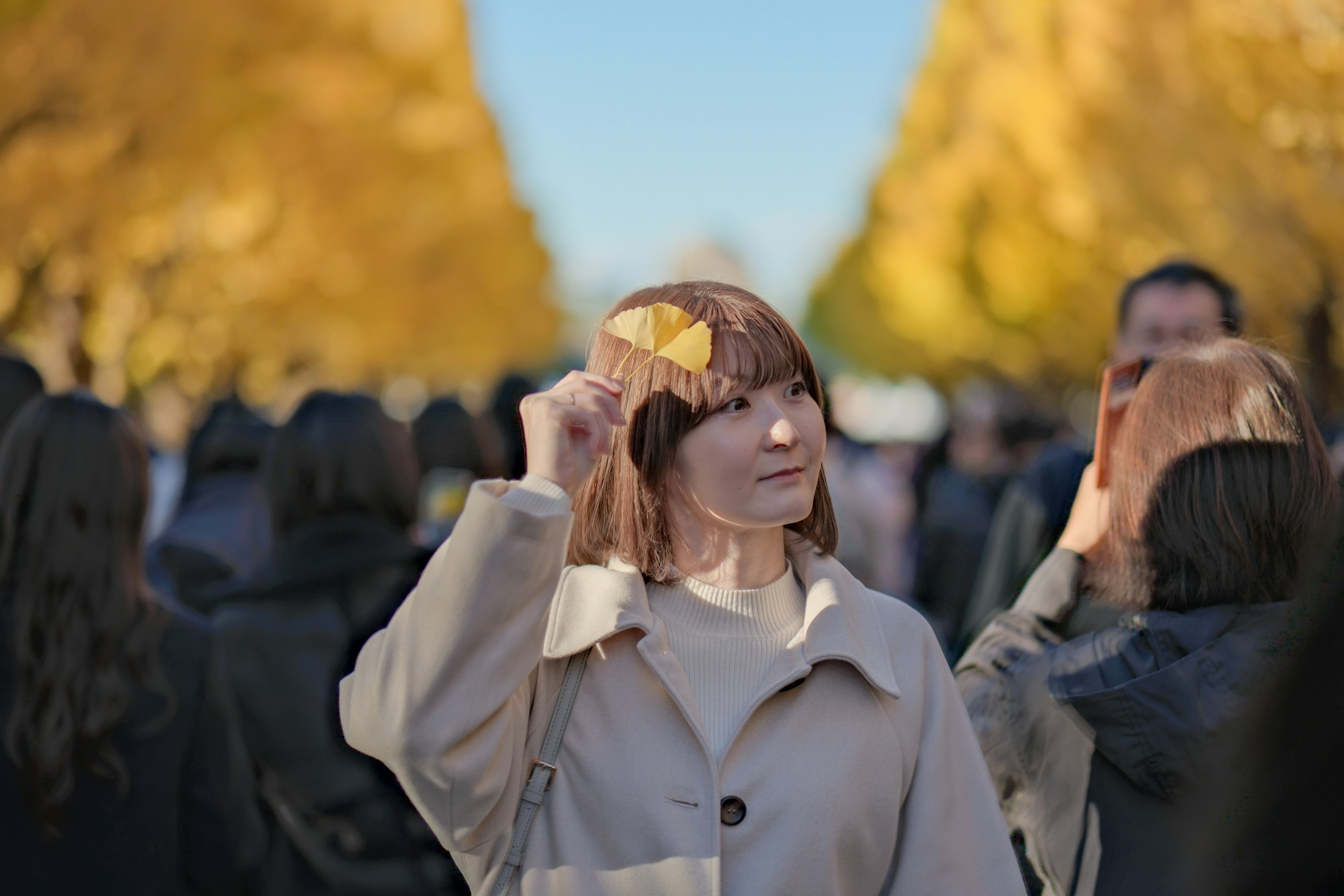 公園で黄色い葉を持つ女性の肖像周囲には多くの人々がいる