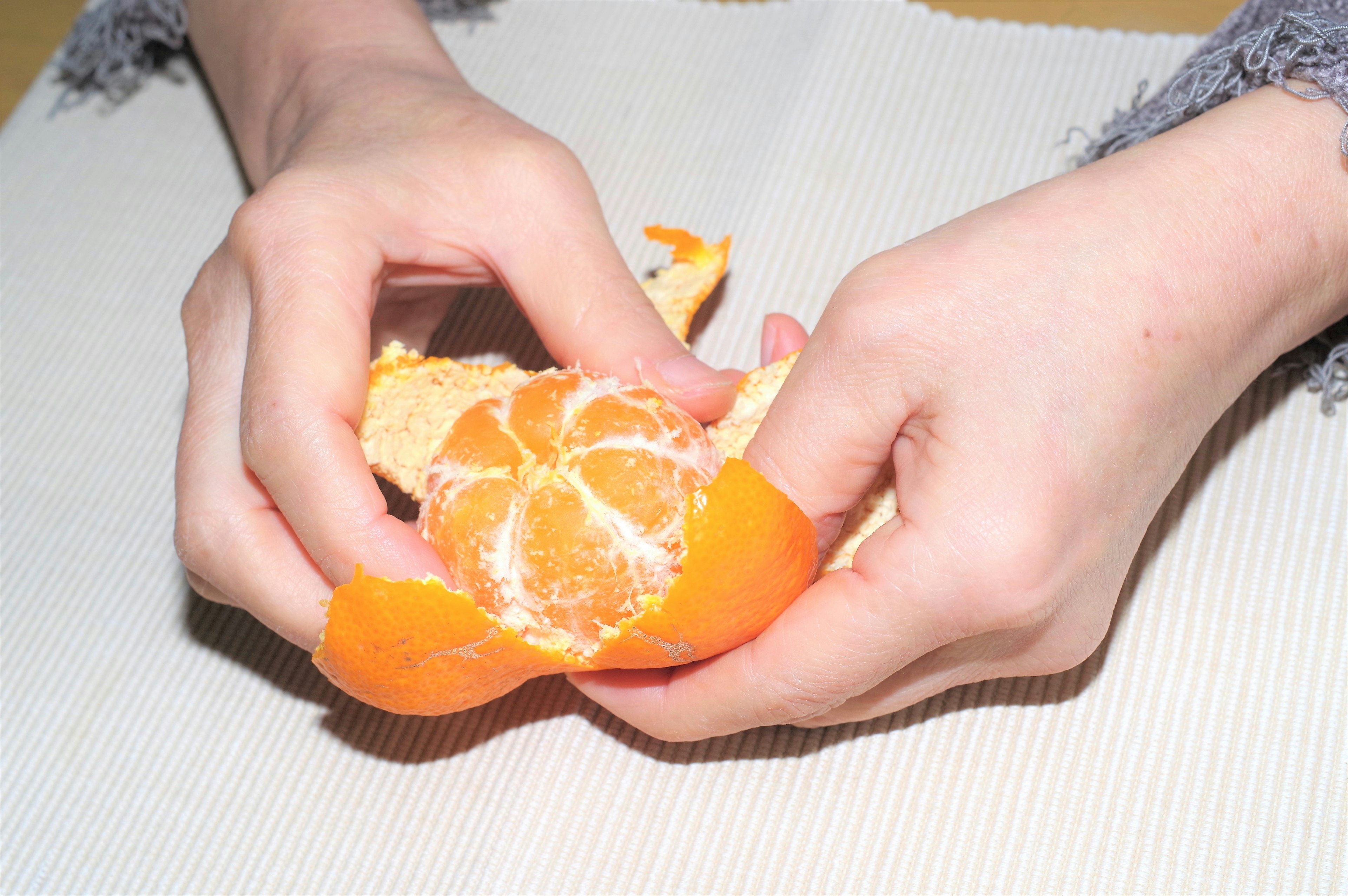 Nahaufnahme von Händen, die eine Orange schälen