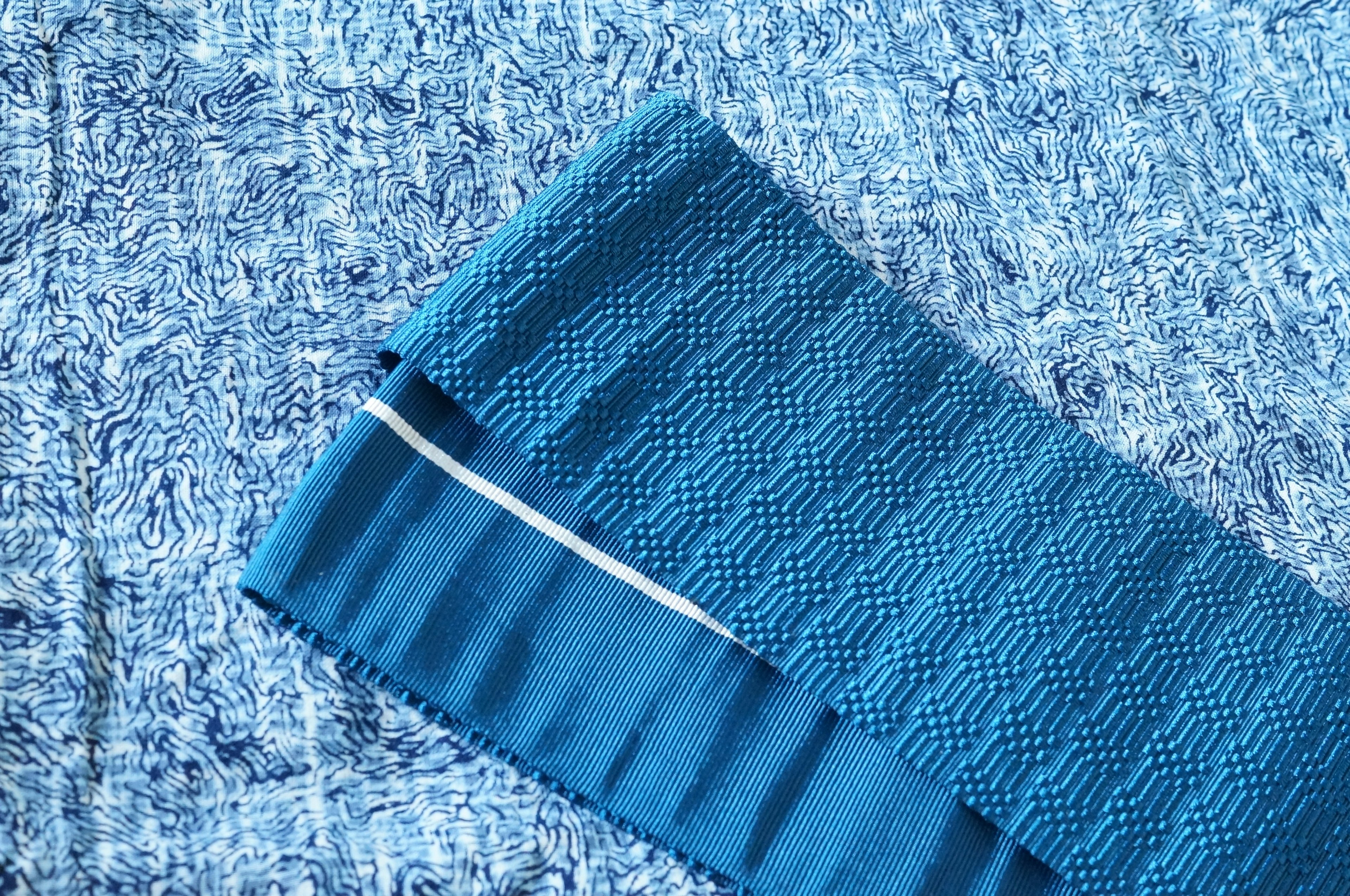 Blue fabric with textured pattern laid on a blue background