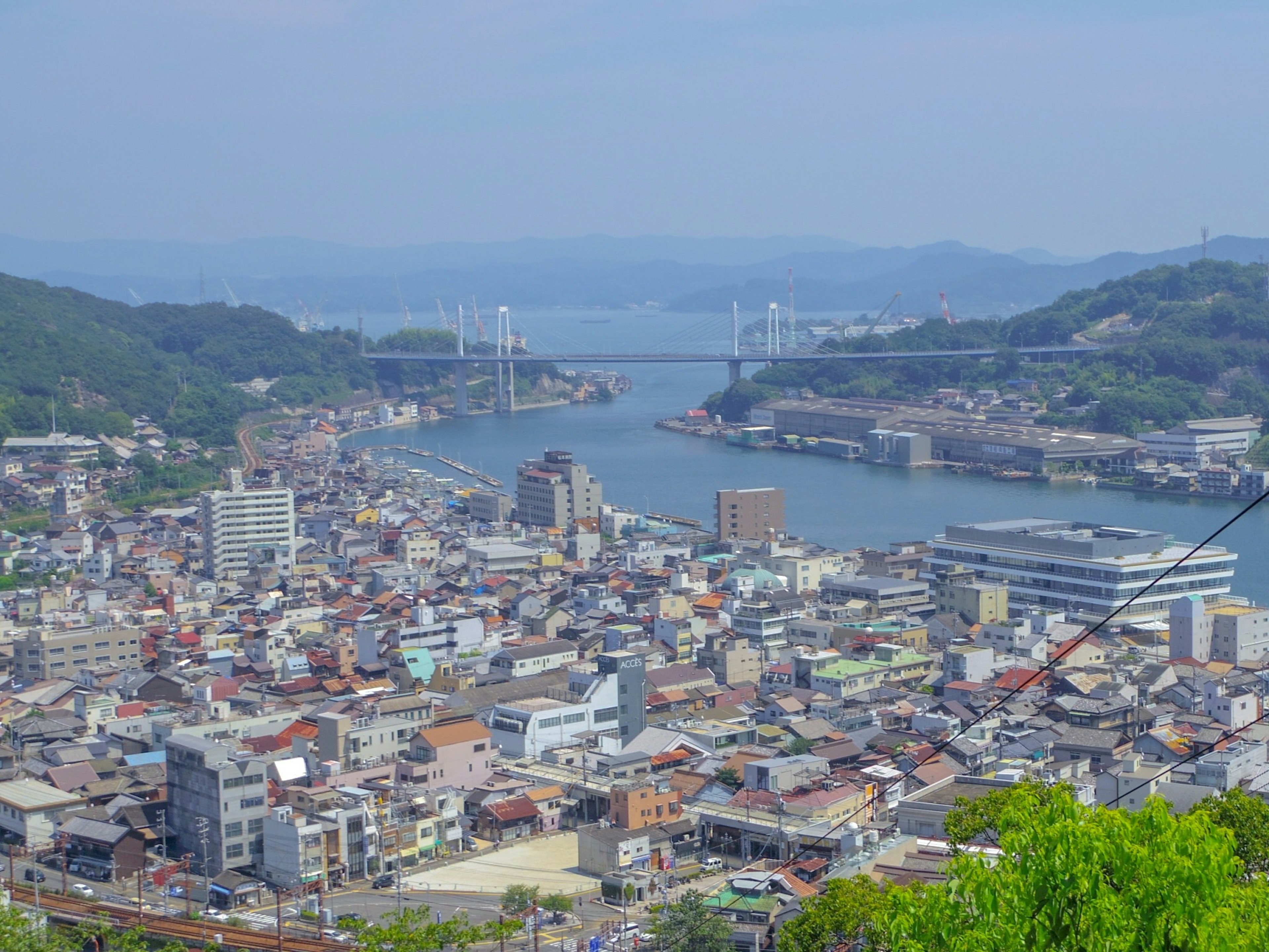 Vista de una ciudad desde una montaña que muestra el mar y puentes