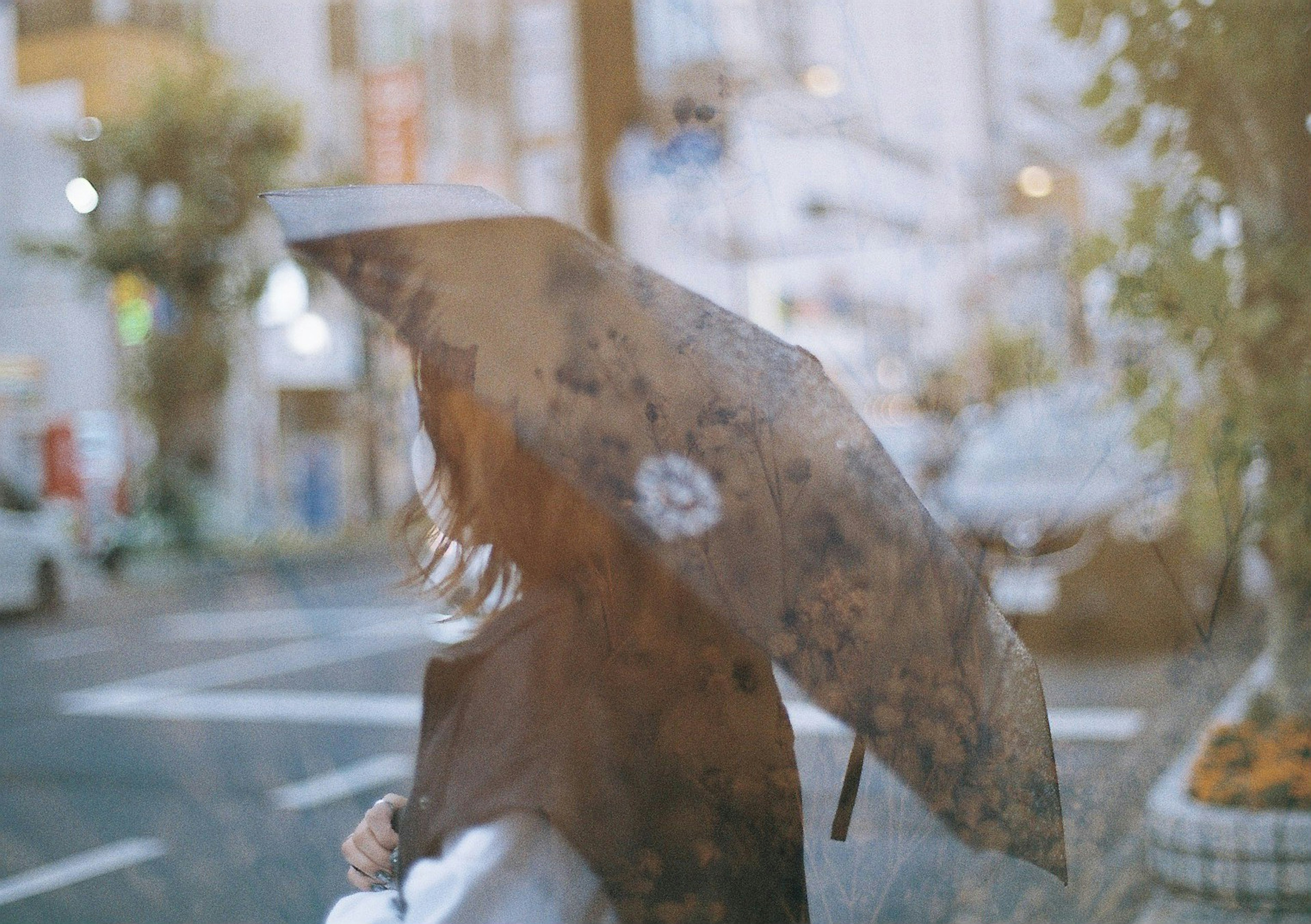 一位女性在雨中撑着伞，模糊的城市背景