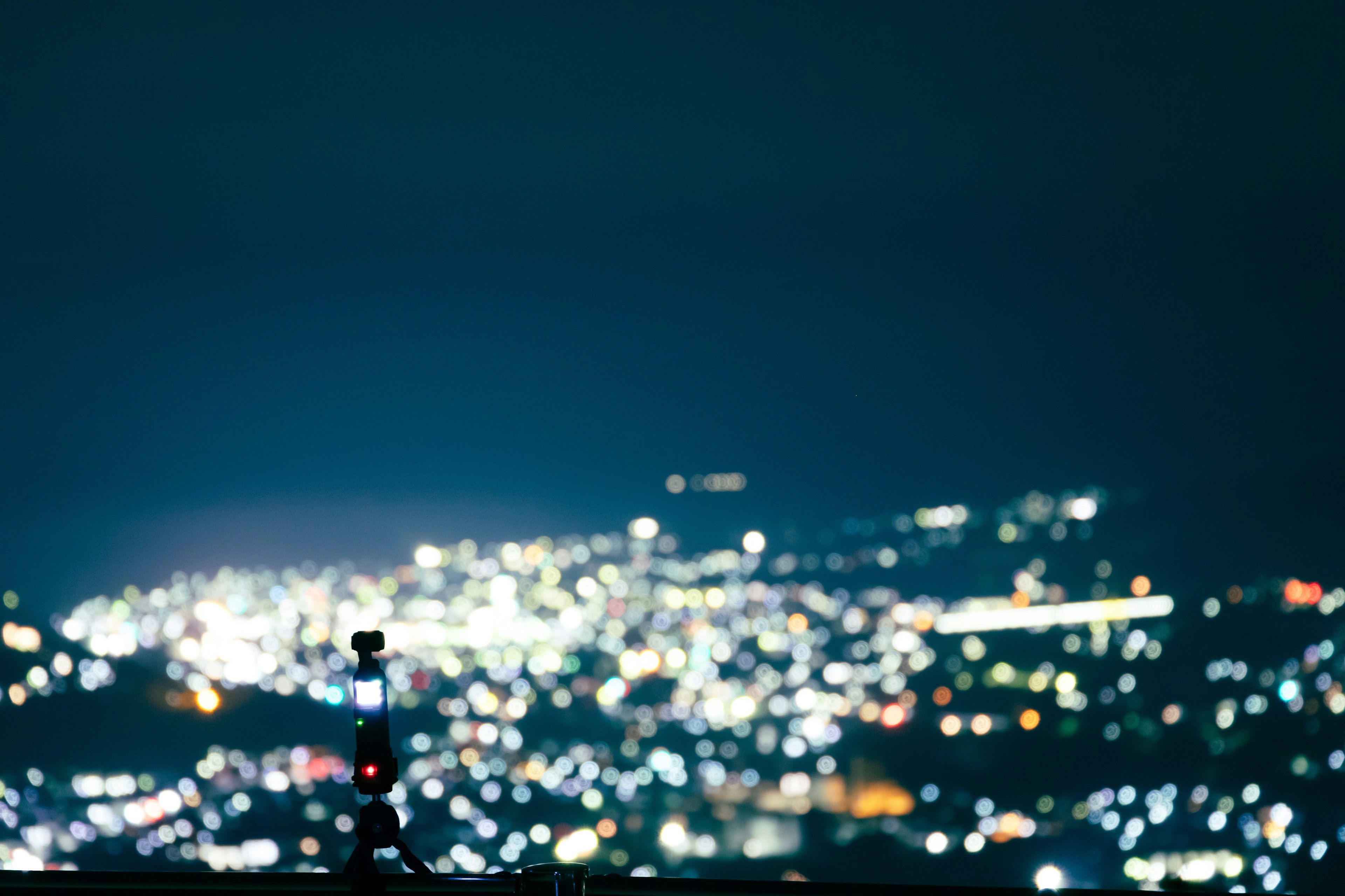 Silhouette eines Stativs vor einer lebhaften Stadtsilhouette bei Nacht