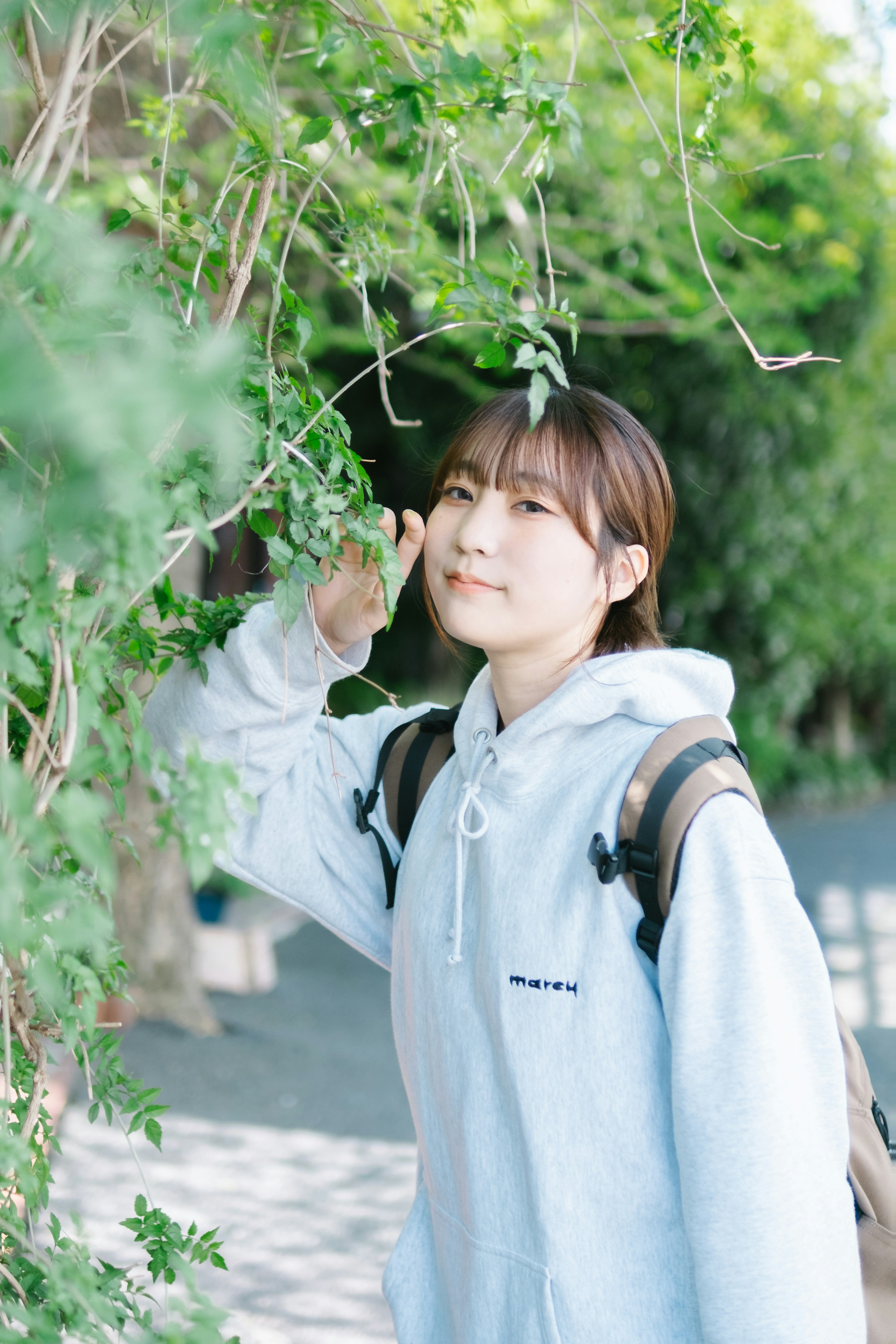 A young woman smiling near green plants