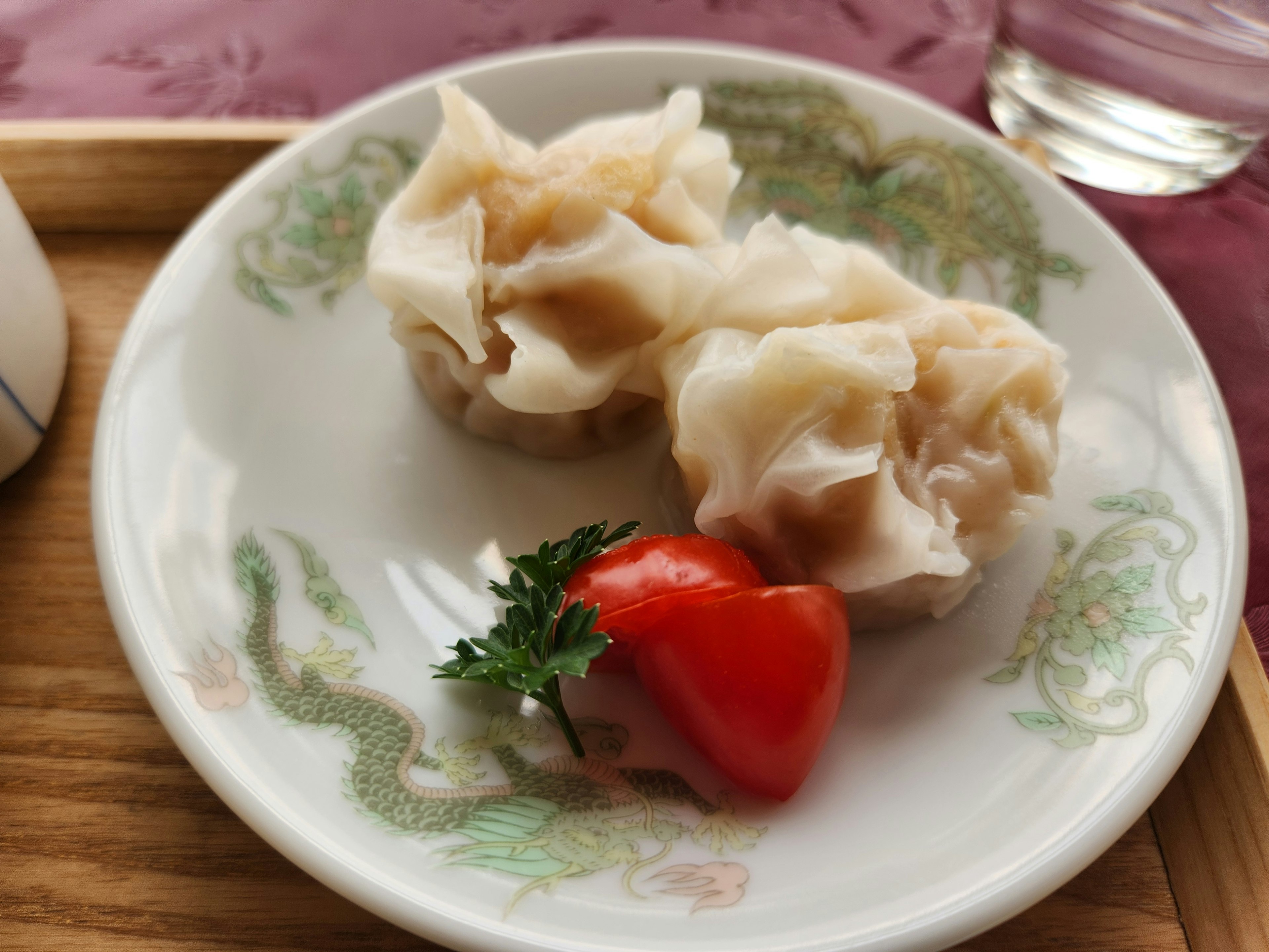 Đĩa có hai viên shumai và một quả cà chua bi