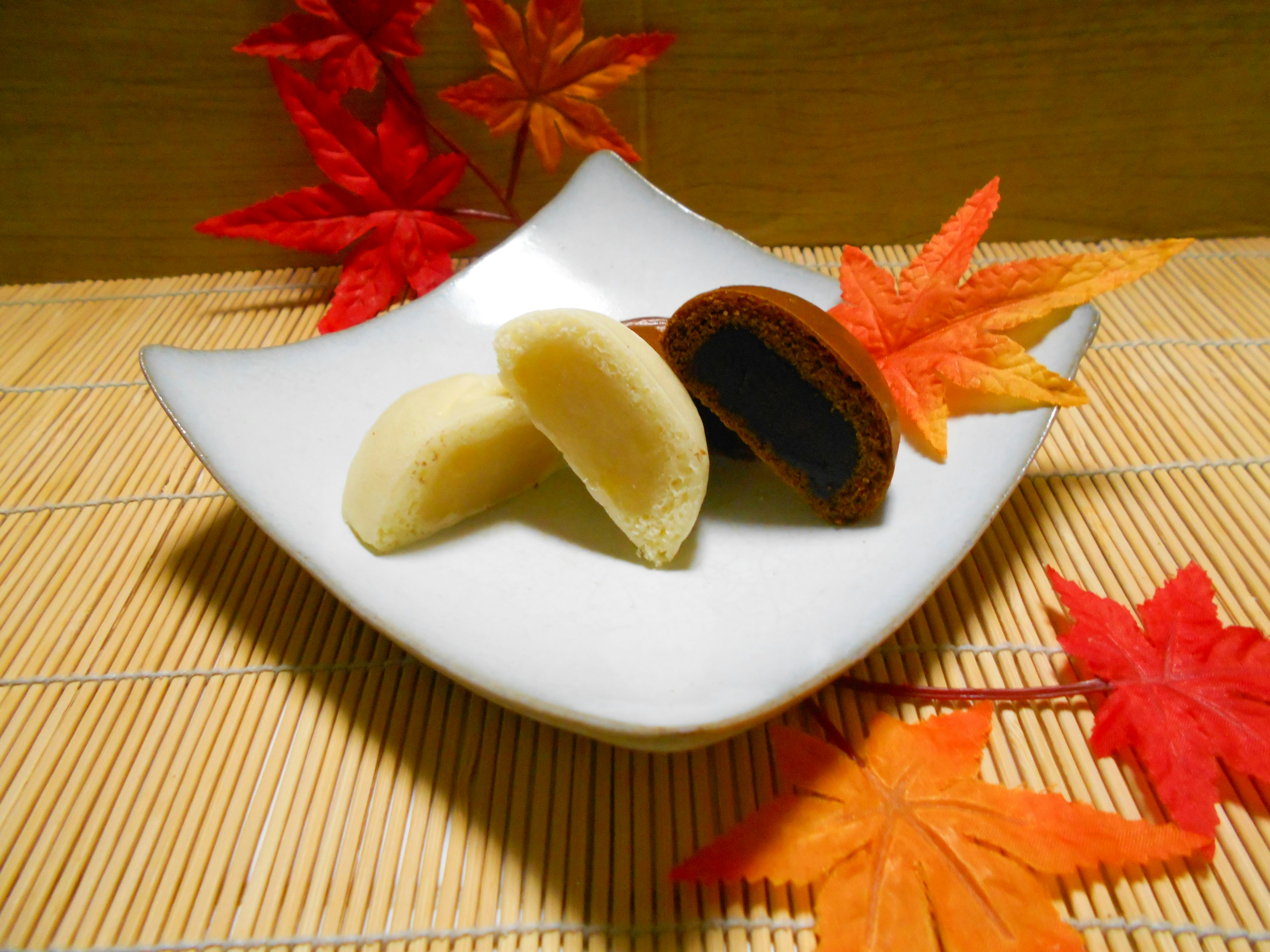 Japanese sweets on a white plate surrounded by autumn leaves