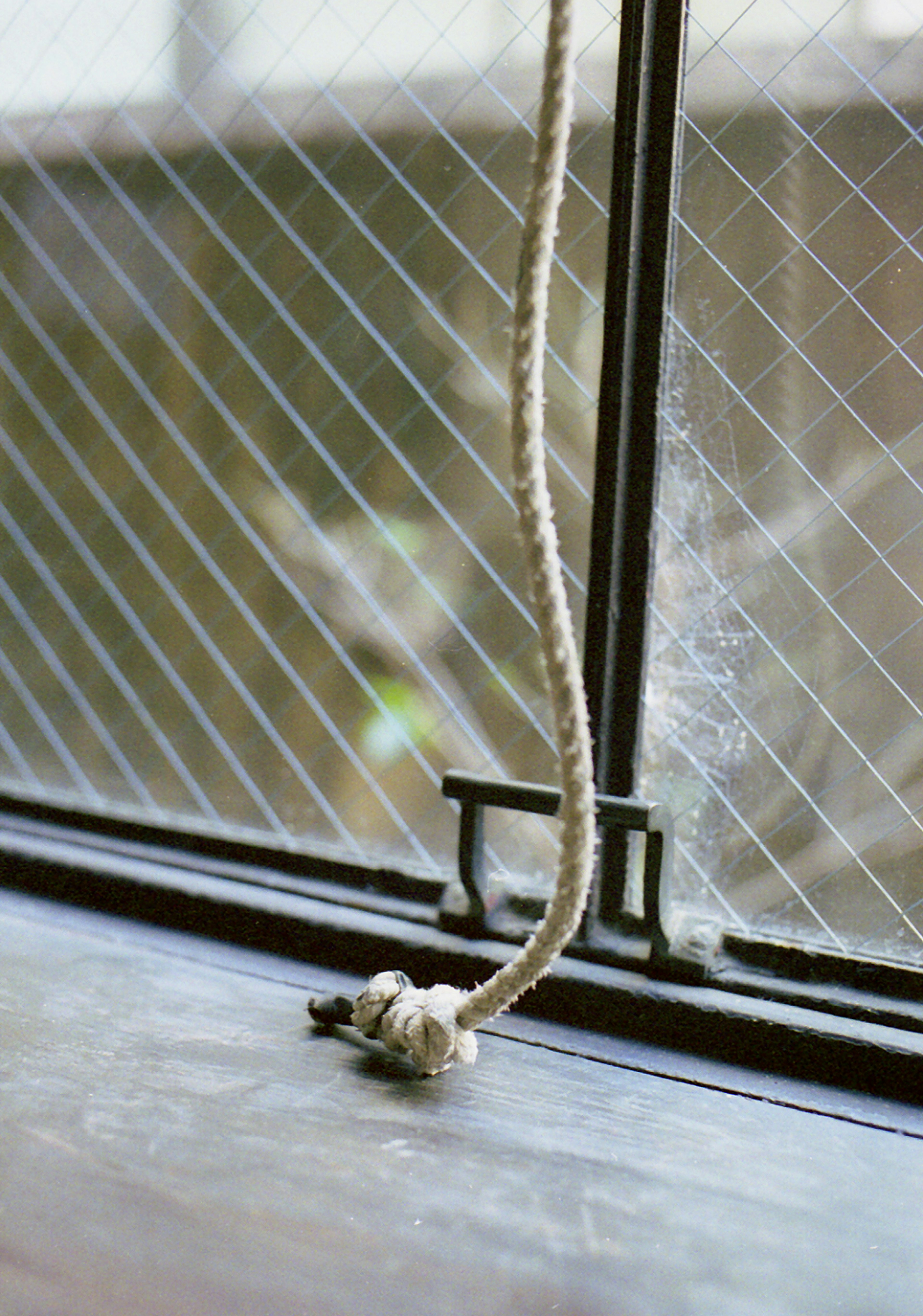 Ein gebundener Strick am Fenster mit einem Gittermuster auf dem Glas