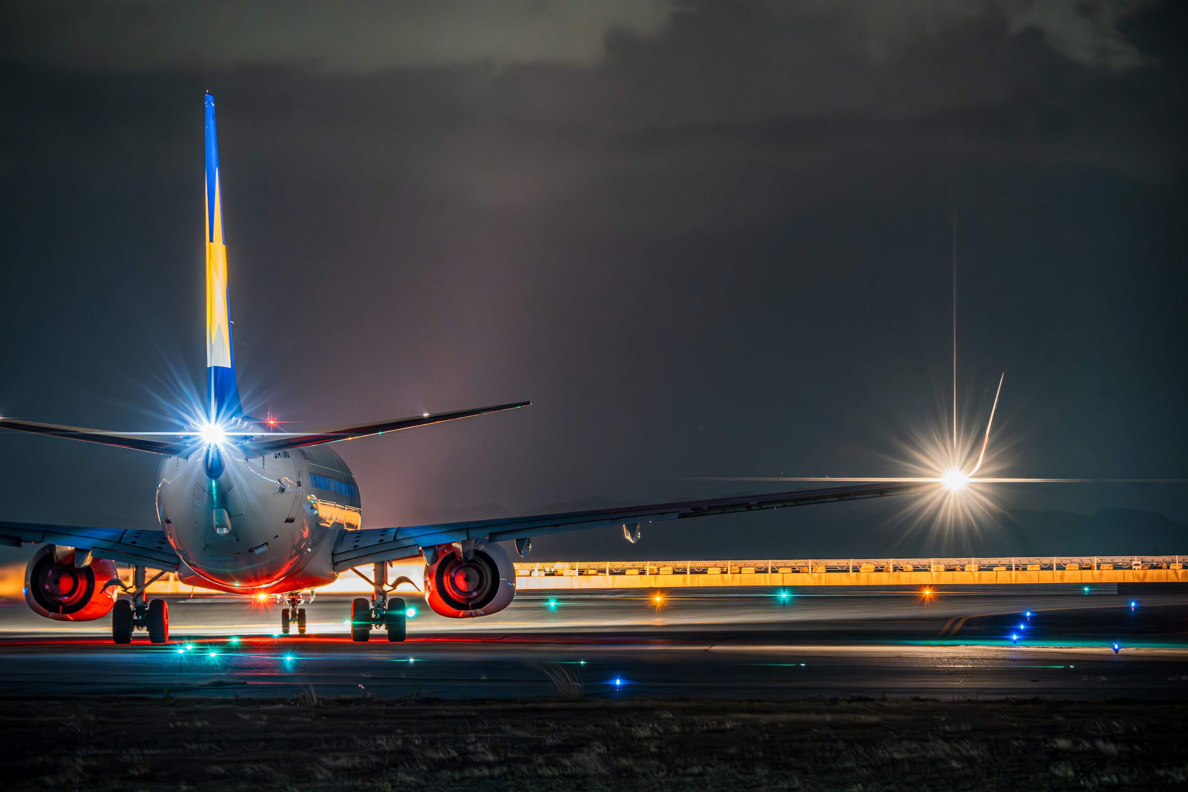 夜の空港で滑走路にいる航空機の後部の明るいライト