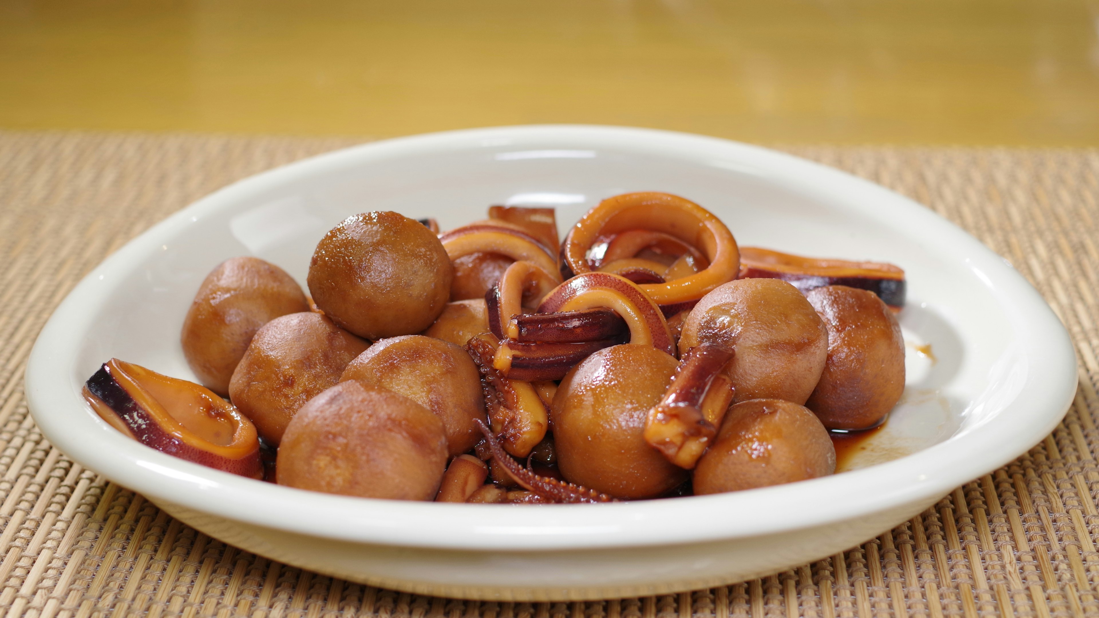 Ein Teller mit kleinen gekochten Tintenfischen in einer würzigen Sauce