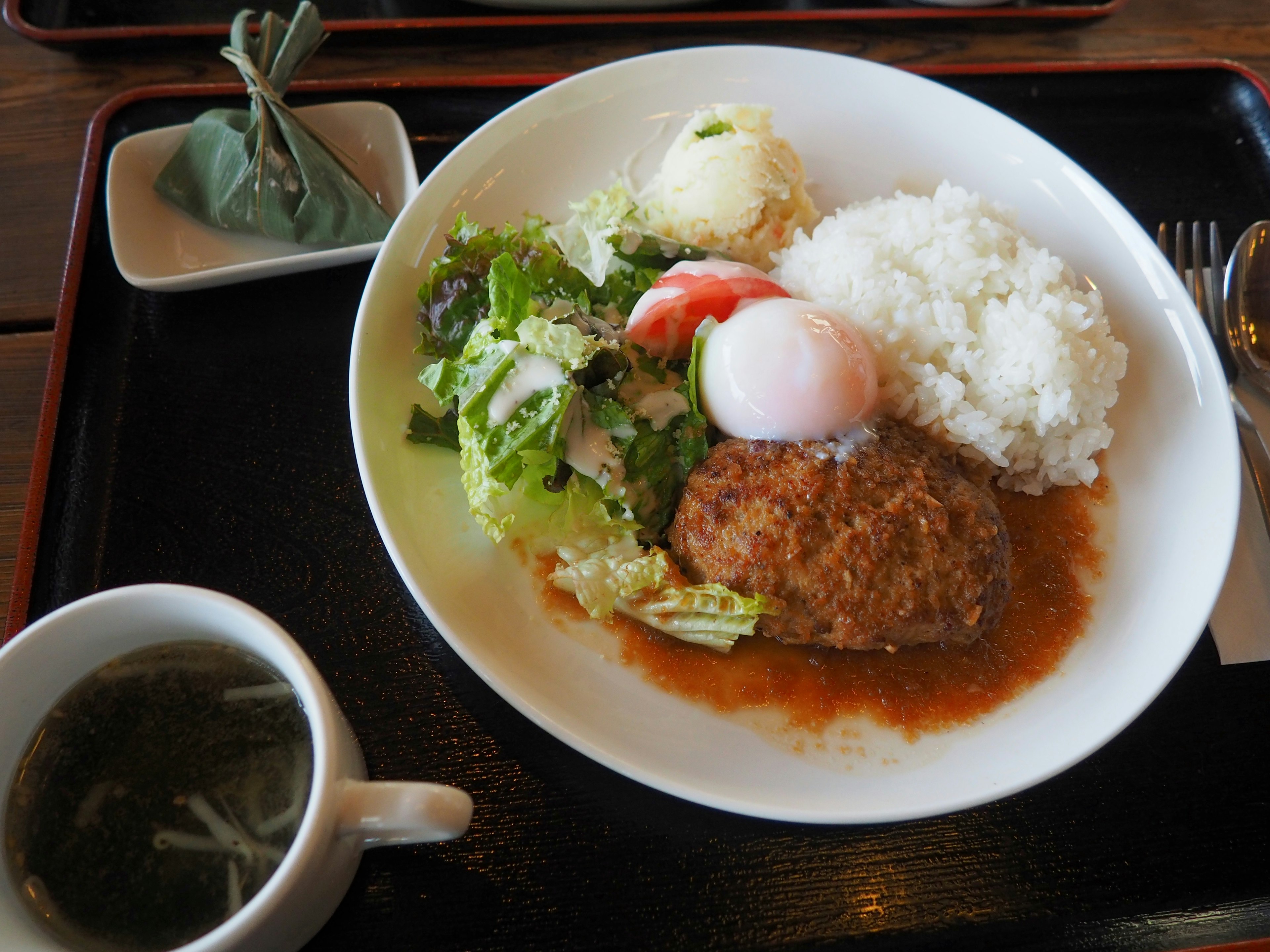 A delicious plate featuring hamburger steak salad rice and soup