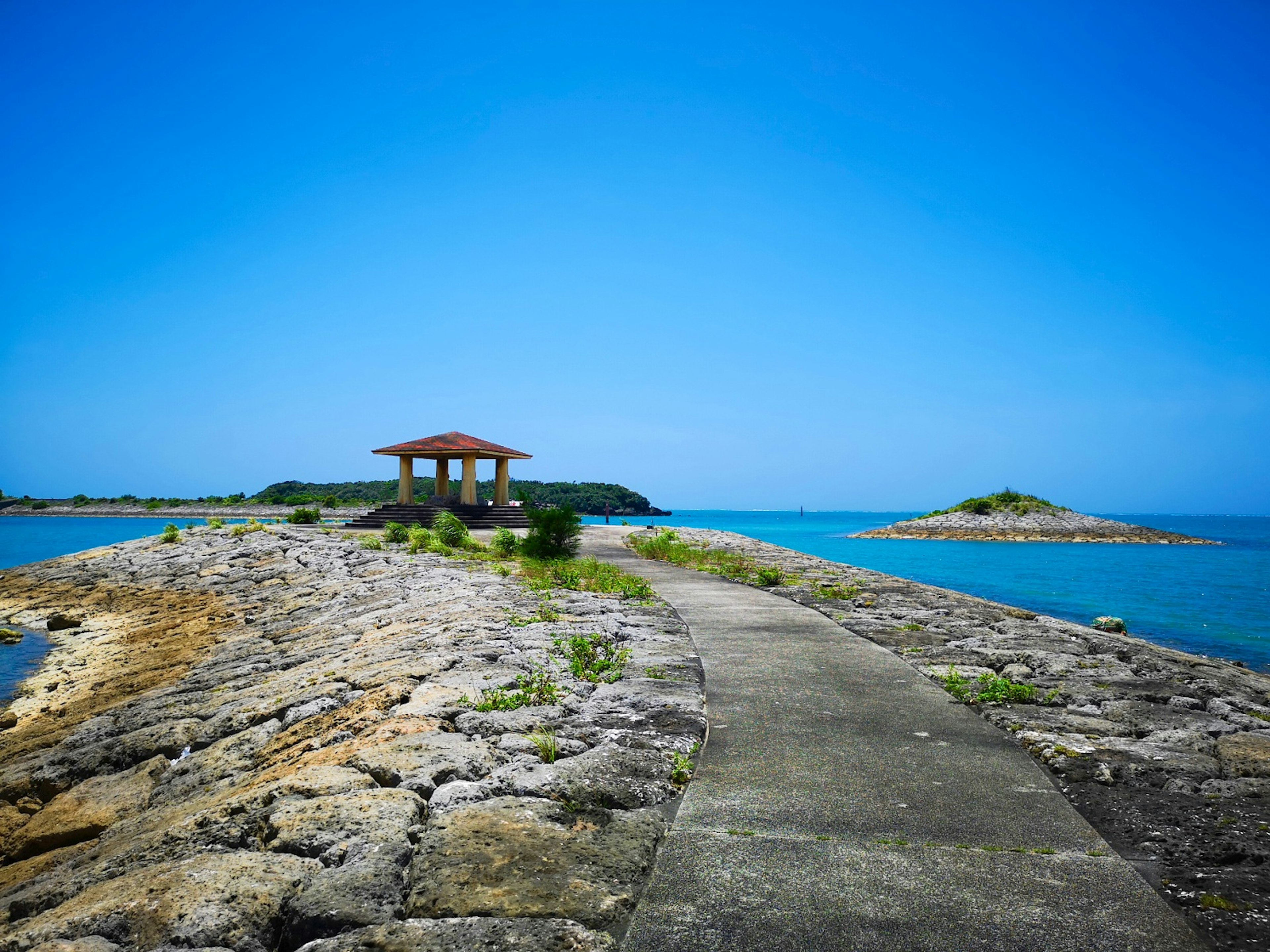 Sentiero che conduce a un gazebo circondato da cielo e mare blu