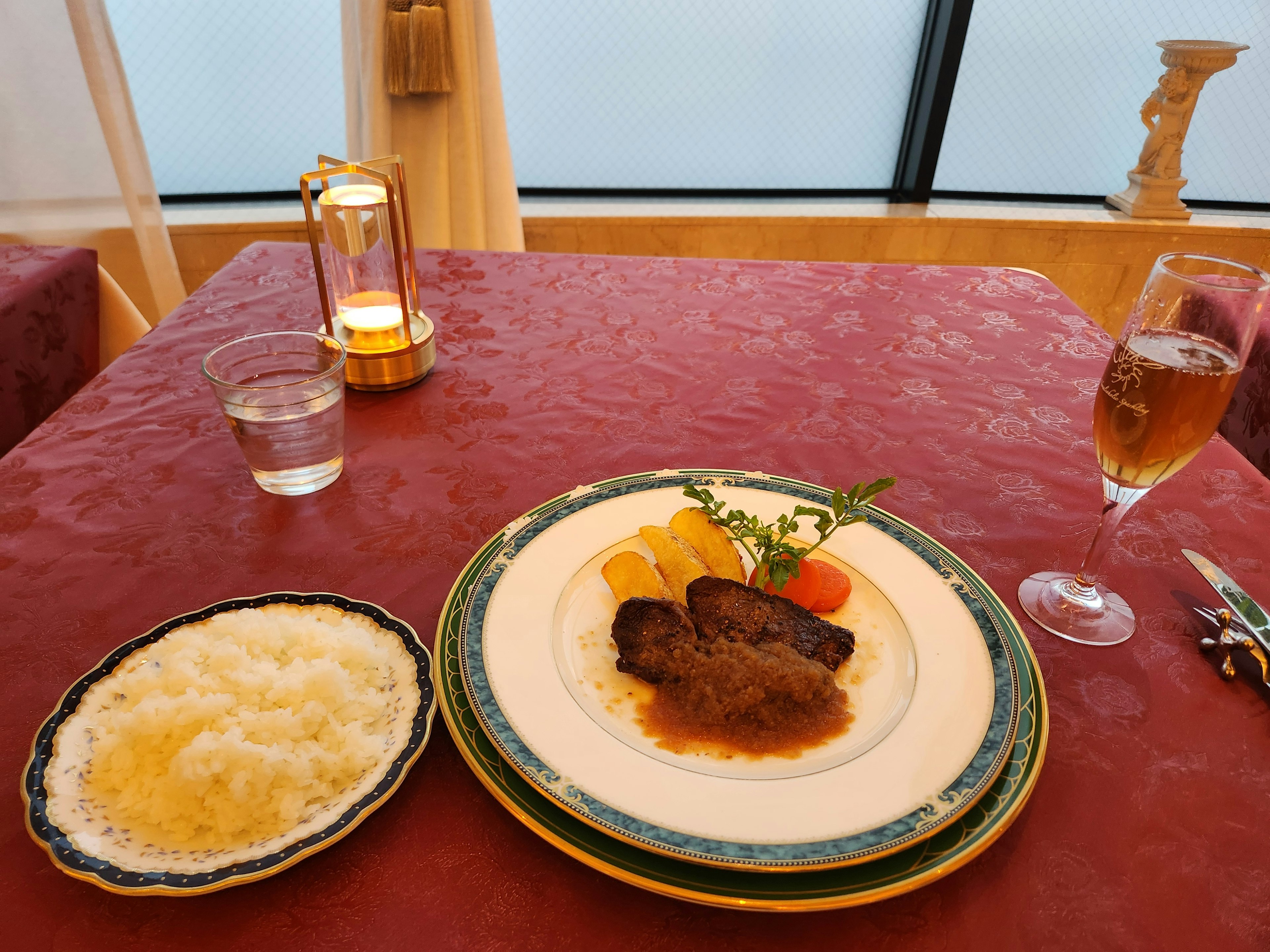 Un piatto di cibo ben presentato su un tavolo con carne in salsa riso e una bevanda