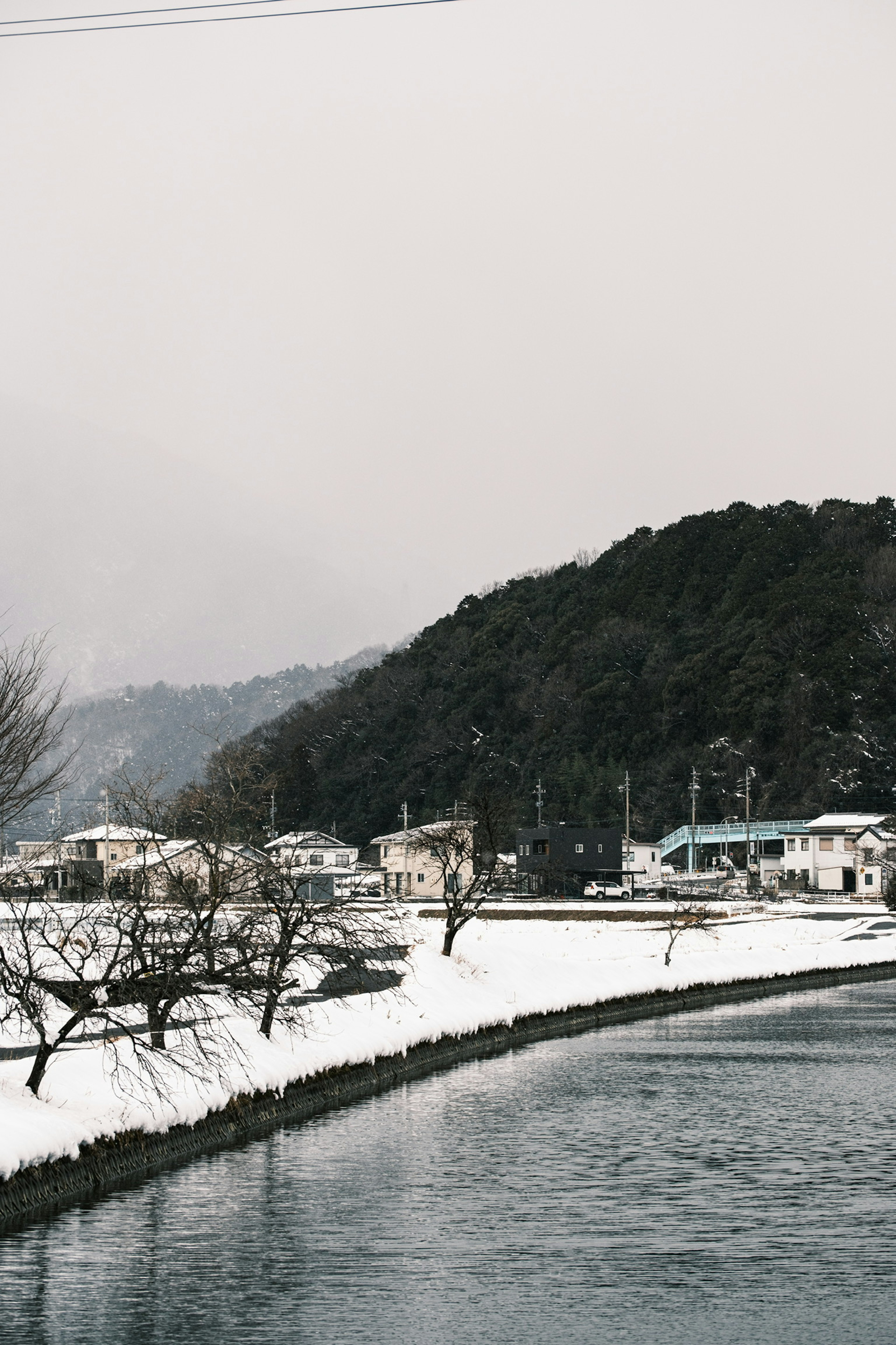 Snow-covered village along a river with mountains in the background