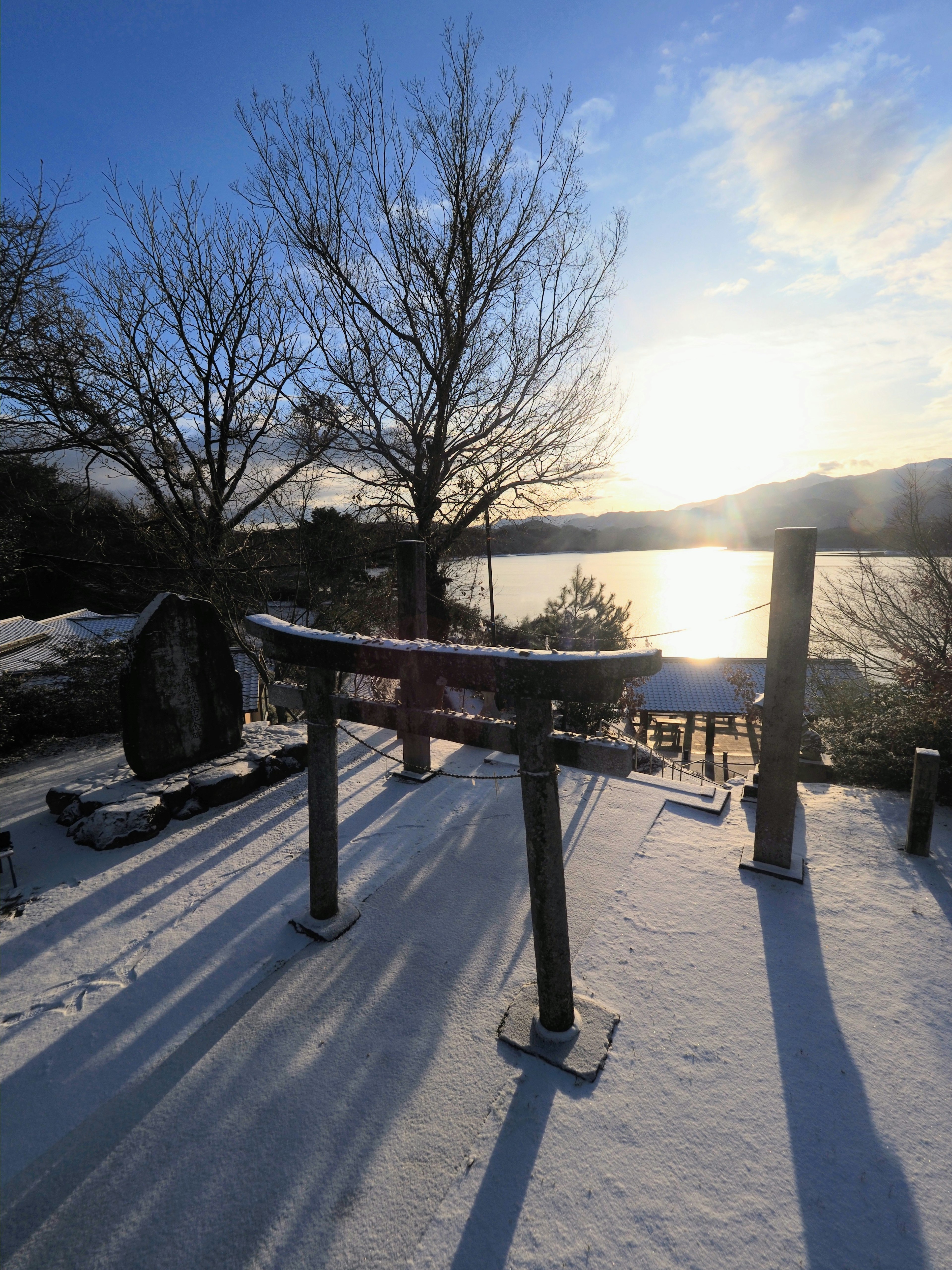 雪に覆われた神社の鳥居と湖の静かな風景