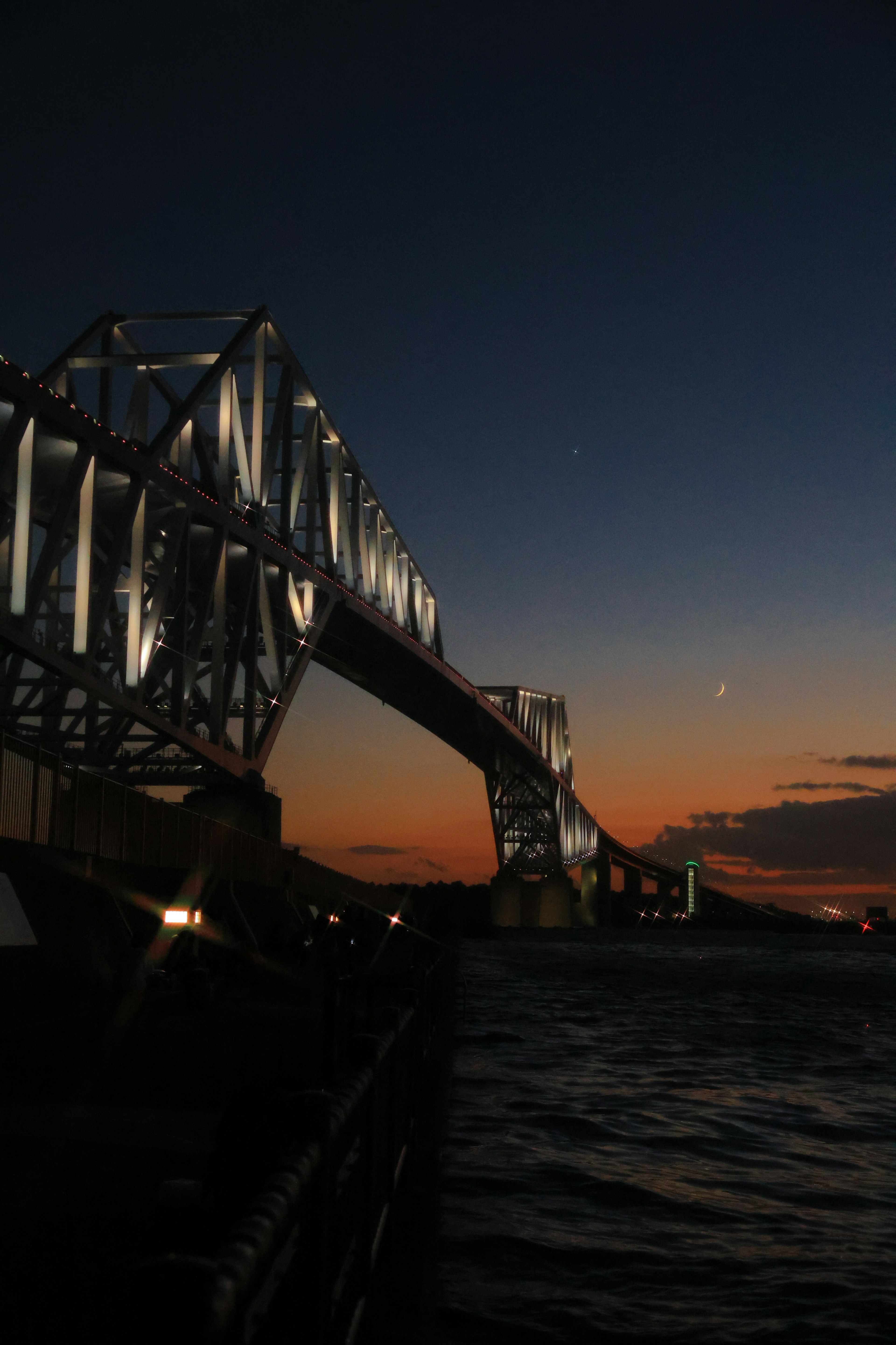 A stunning view of a bridge illuminated at night over water