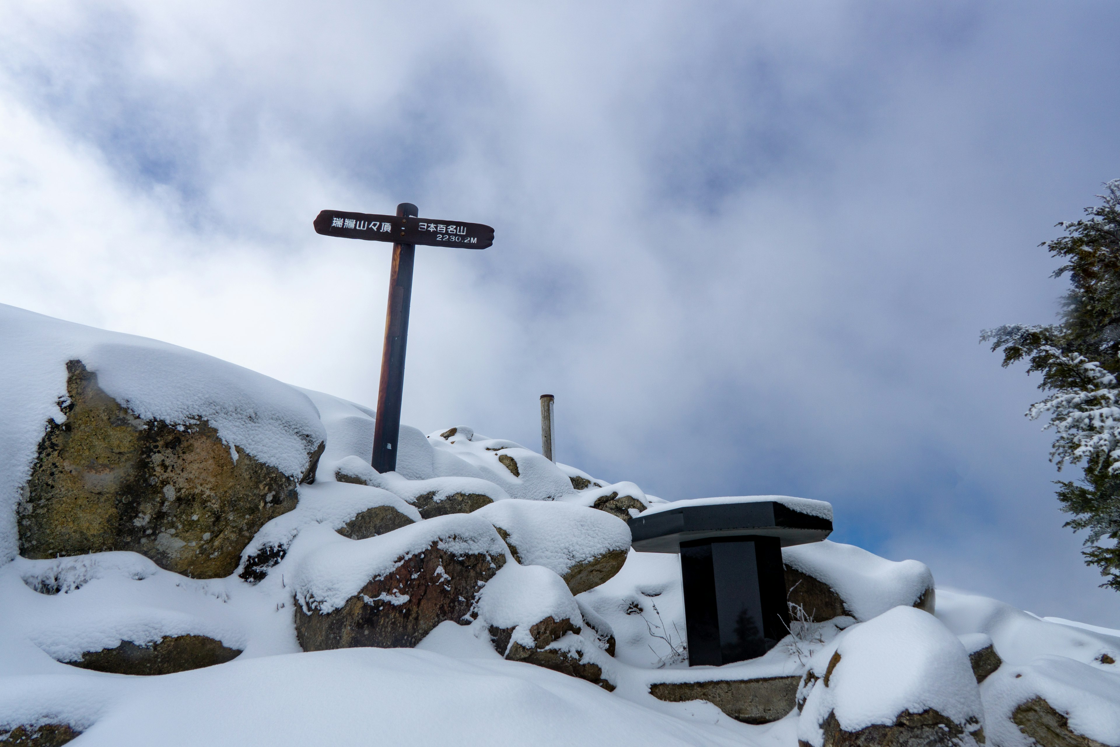 Signpost and bench on snow-covered rocks