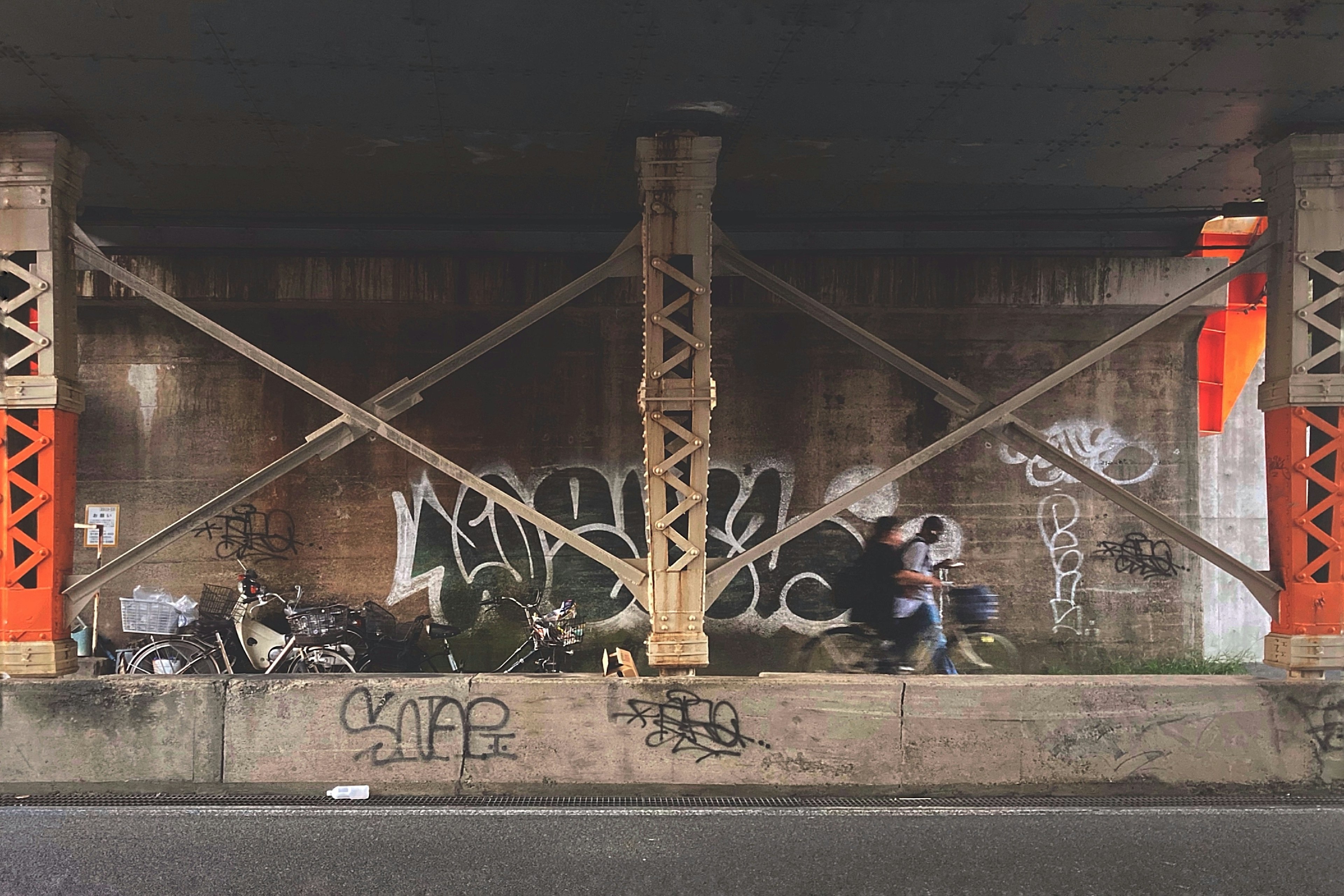 Des personnes assises sous un pont avec des graffitis sur un mur en béton