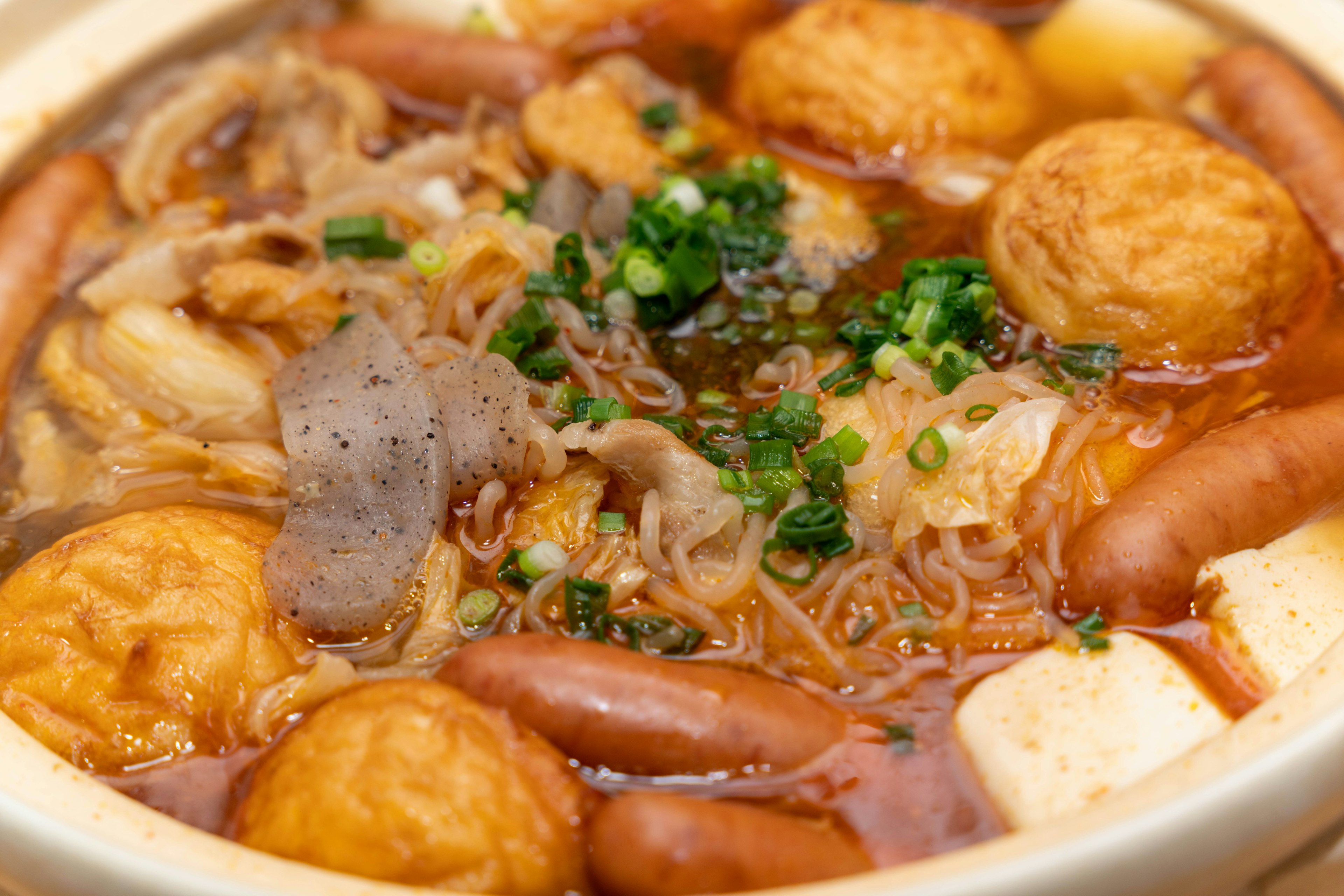 A close-up of a hearty soup with various ingredients including meat, fish balls, and vegetables