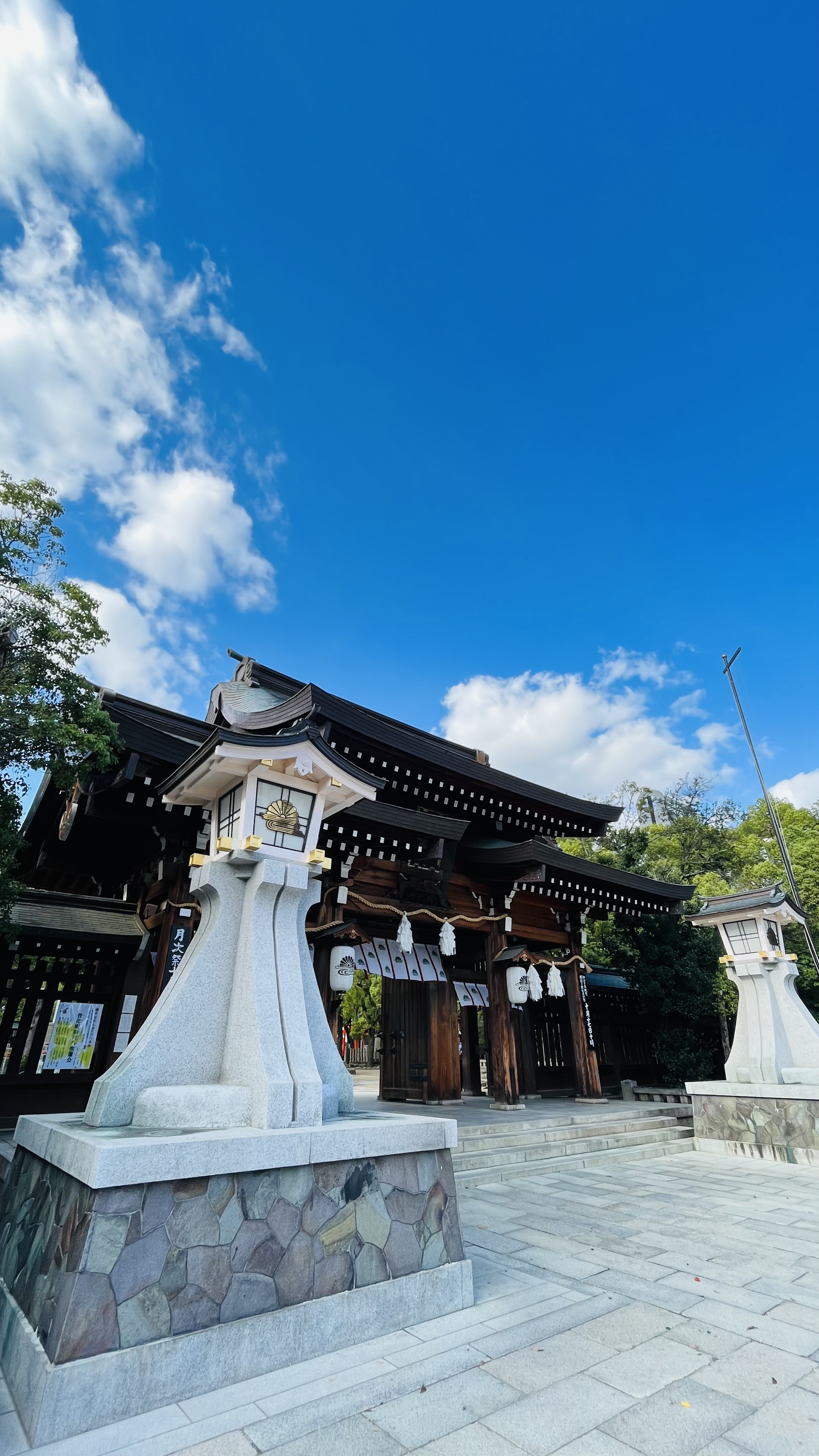 青空の下にある伝統的な日本の神社の入口と石灯籠