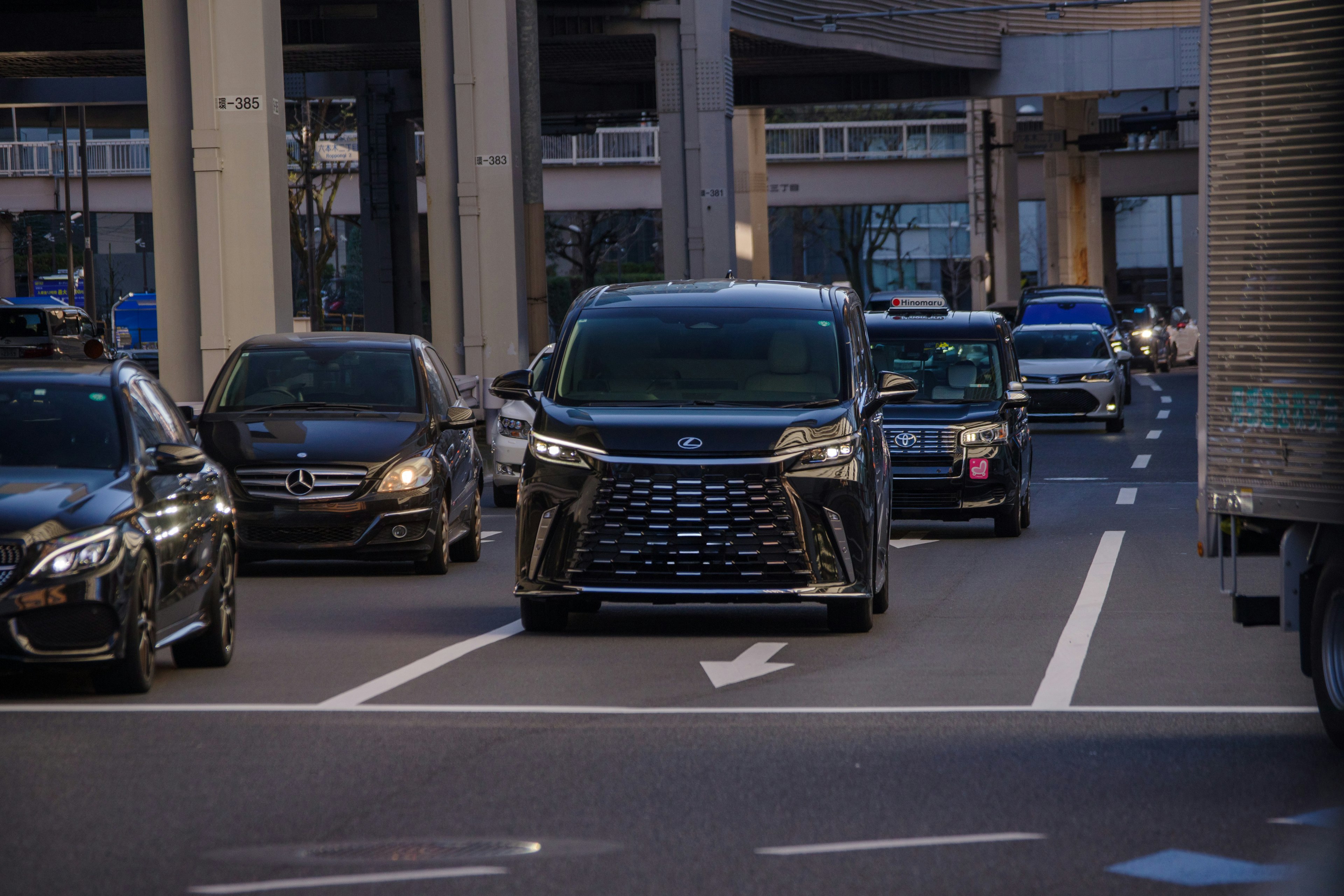 都市の道路を走る黒いミニバンと他の車両群