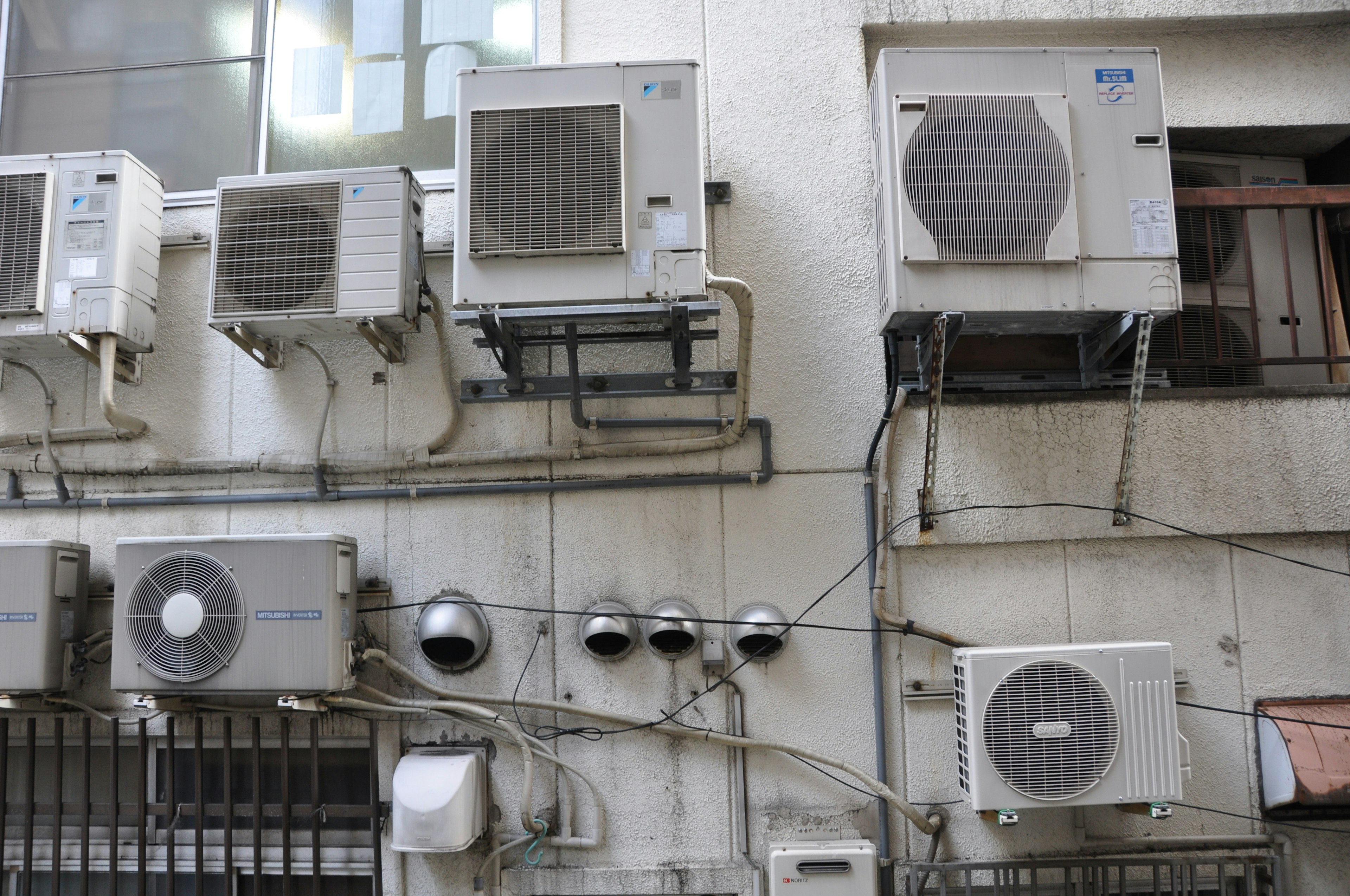 Multiple air conditioning units and pipes mounted on a building exterior