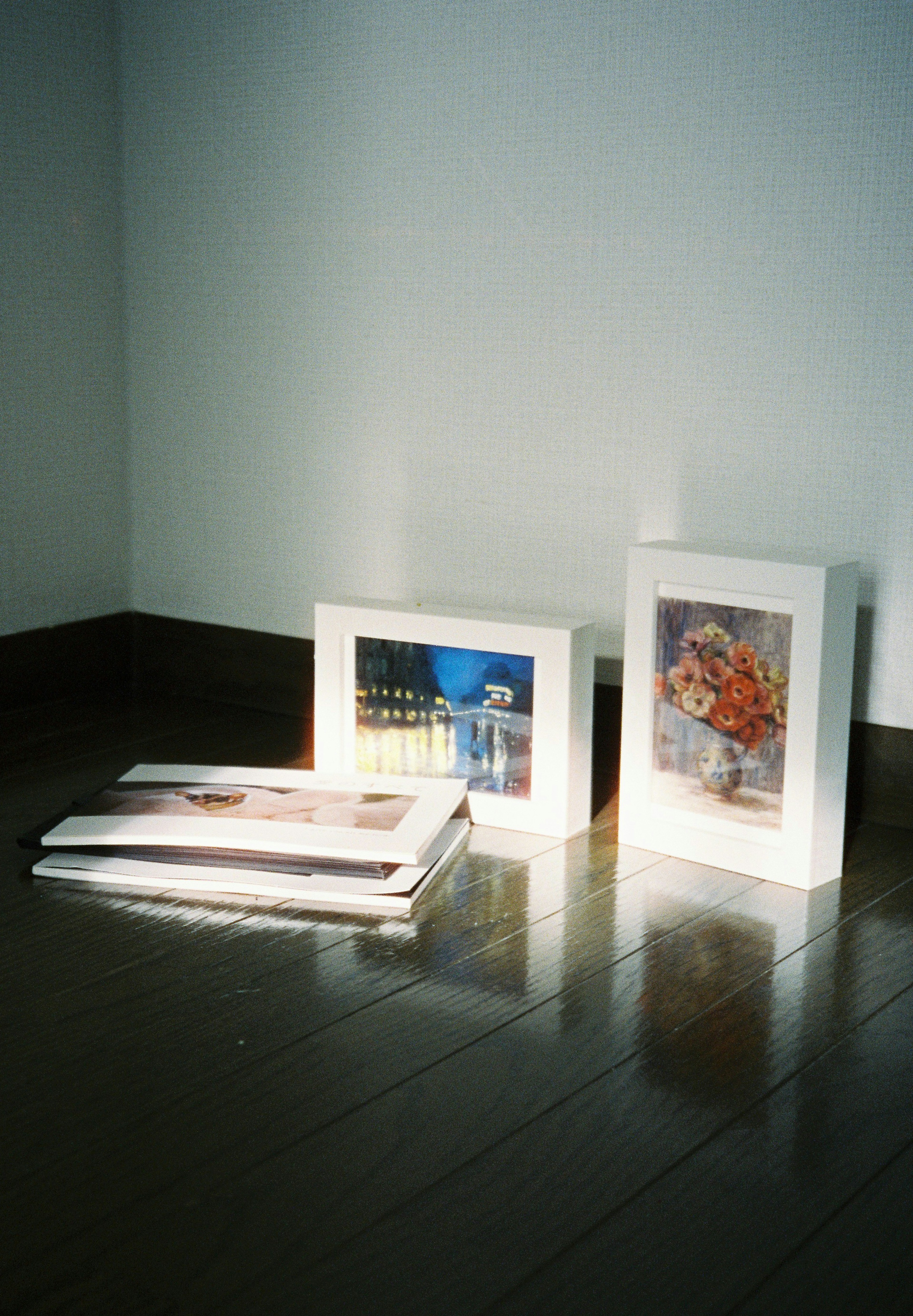 A simple indoor scene featuring framed photos and books on the floor