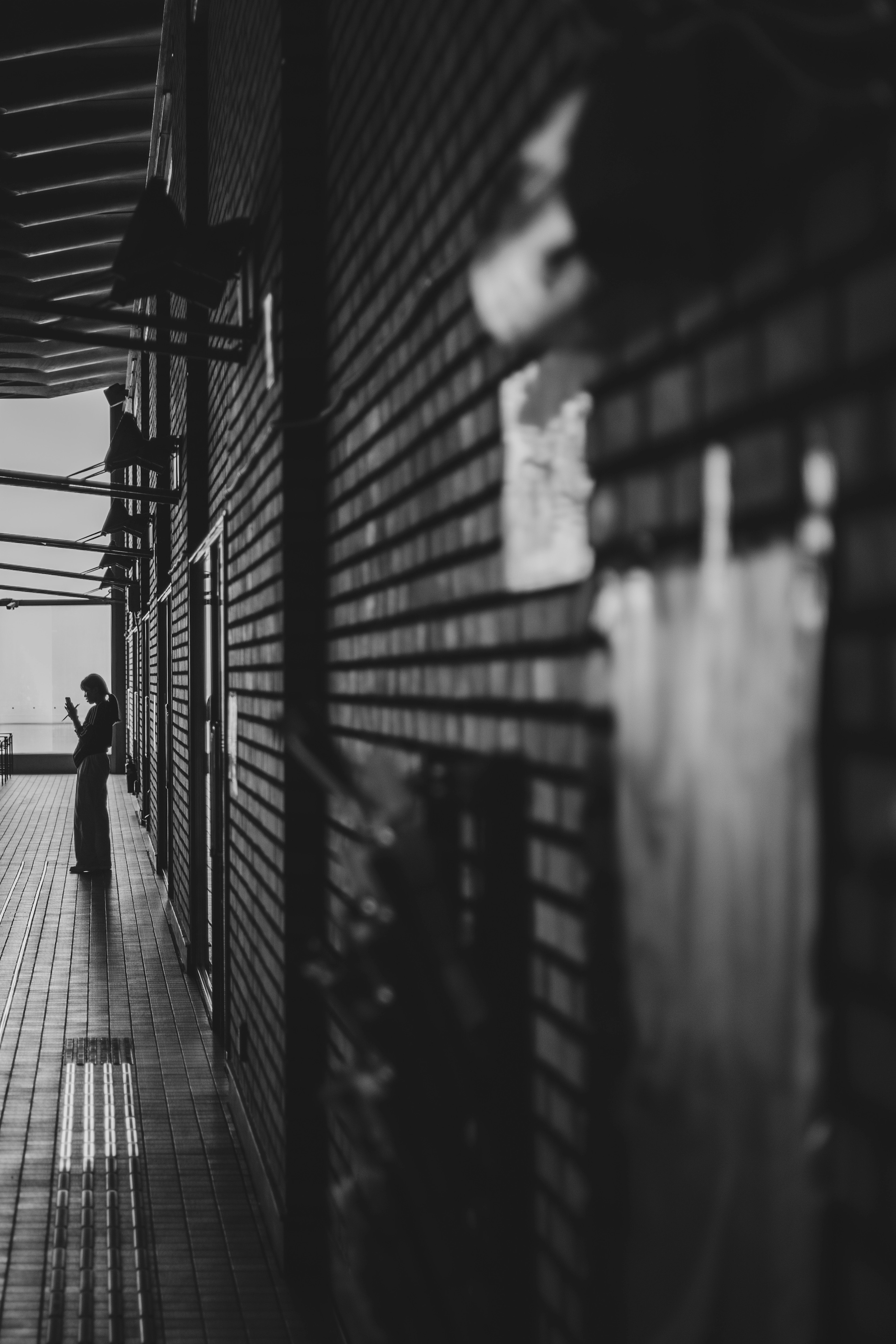 Silhouette d'une personne dans un couloir monochrome avec des murs en briques