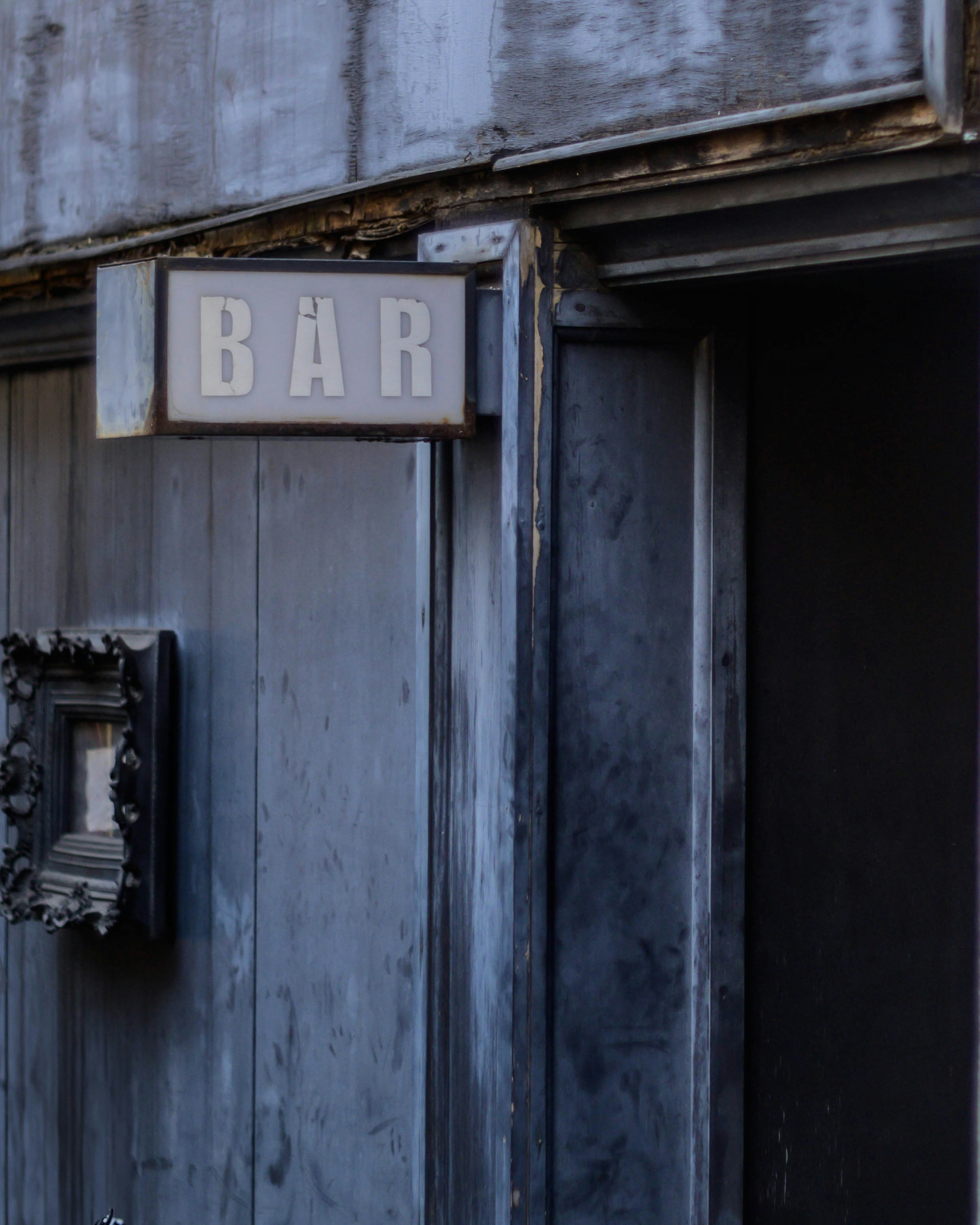 A weathered wooden door featuring a bar sign