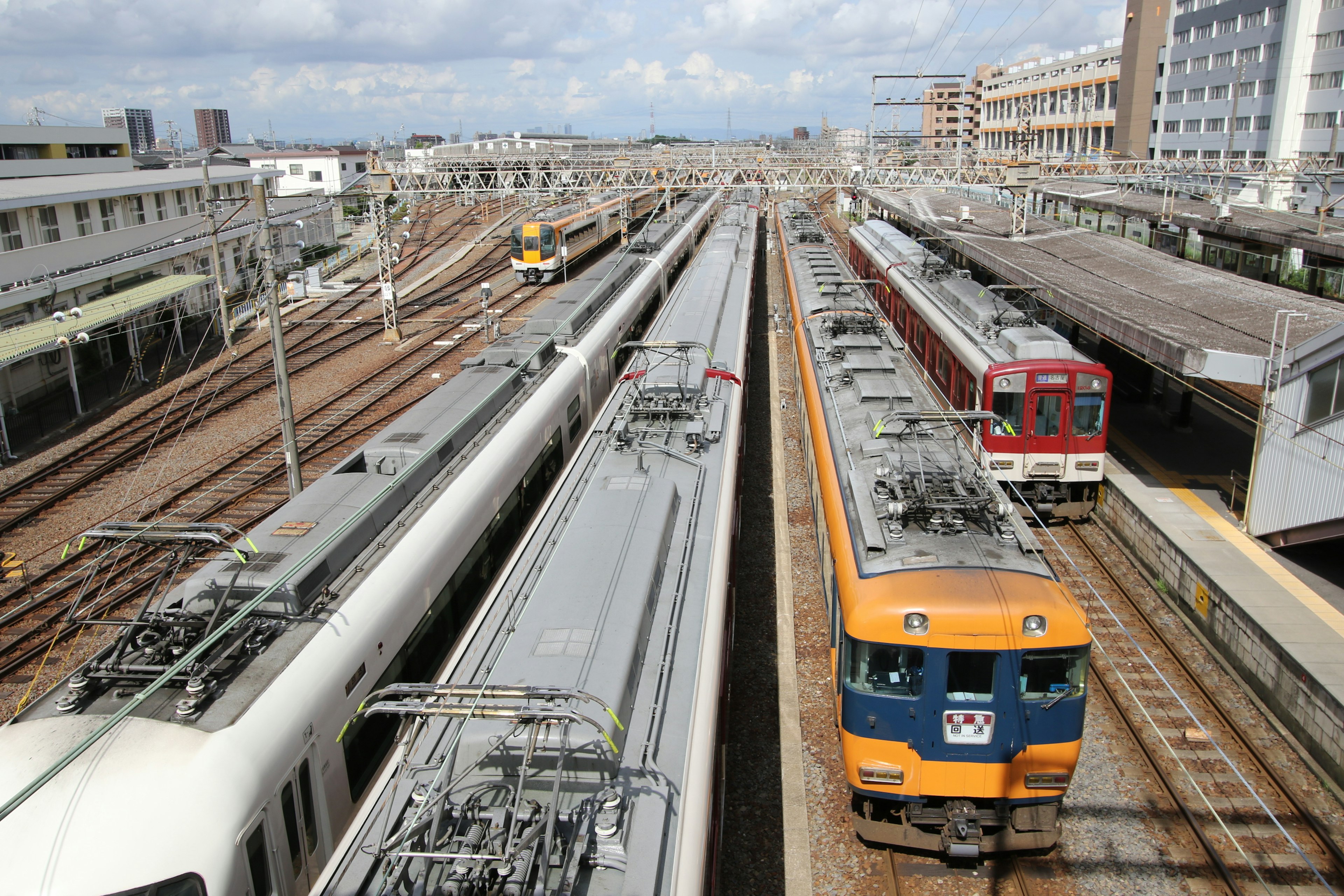 鉄道の駅で複数の列車が並ぶ光景青空と雲が広がる背景