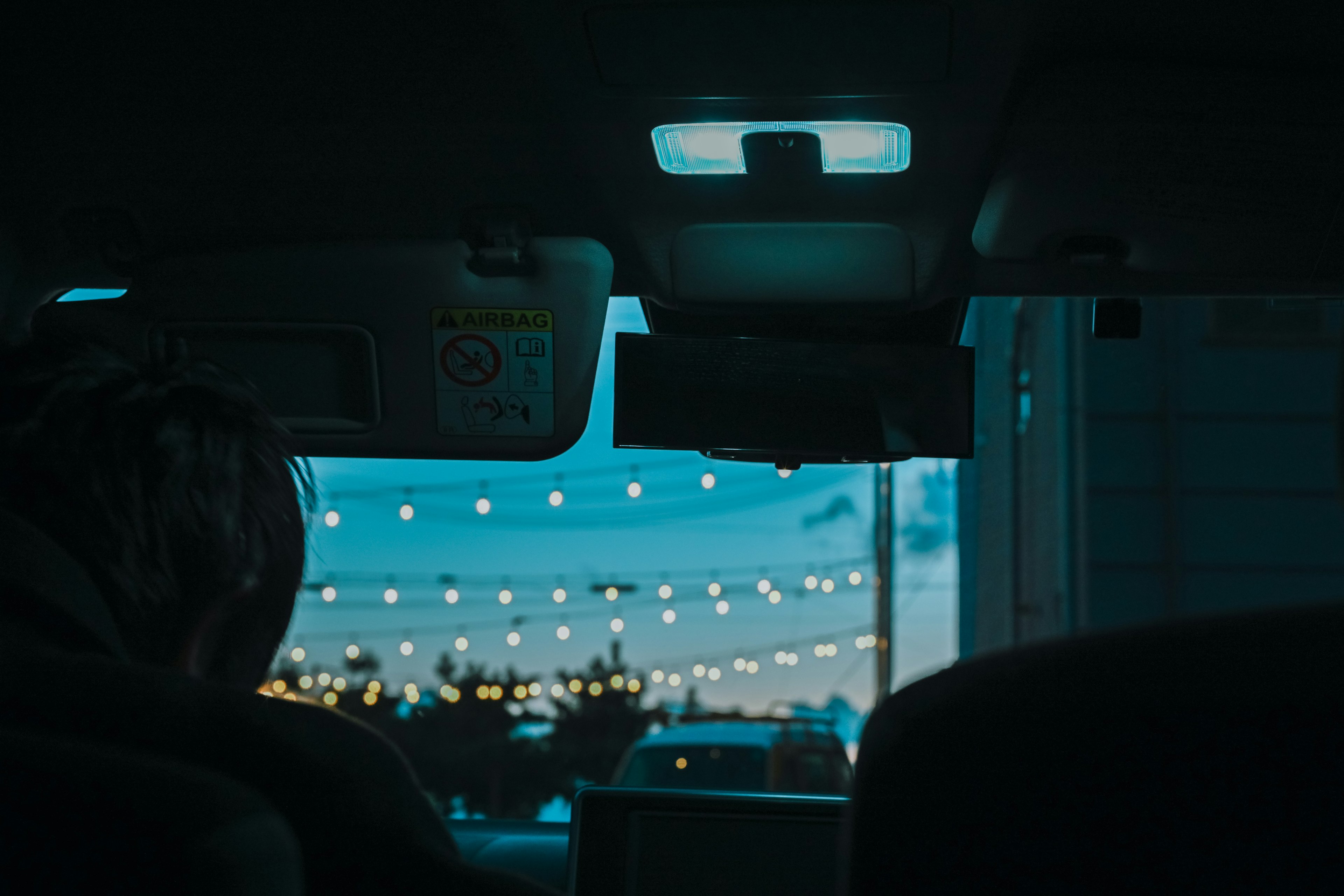 Vue de l'intérieur d'un véhicule montrant des lumières du soir et une lumière bleue au plafond