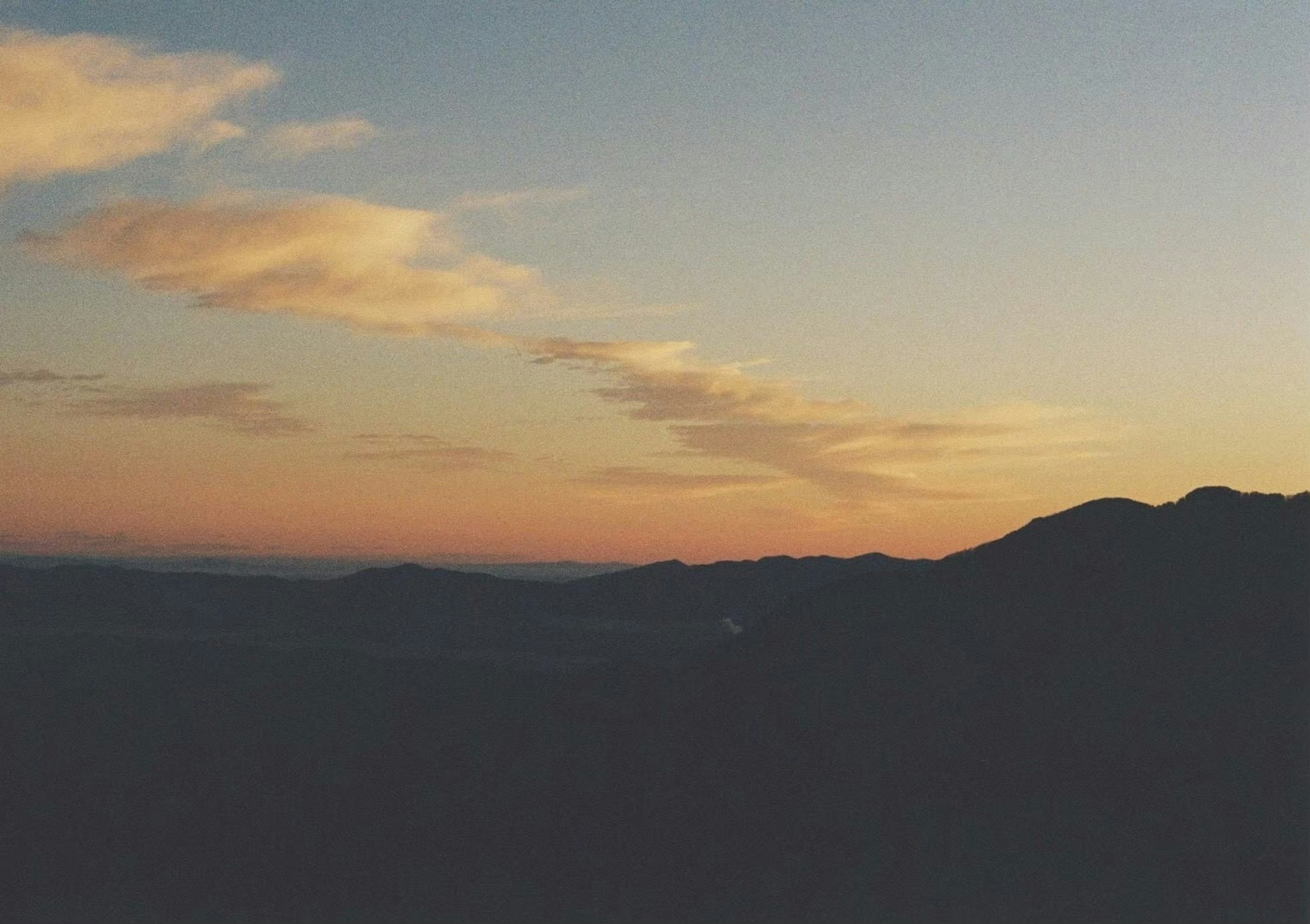 Silhouette of mountains at sunset with streaked clouds