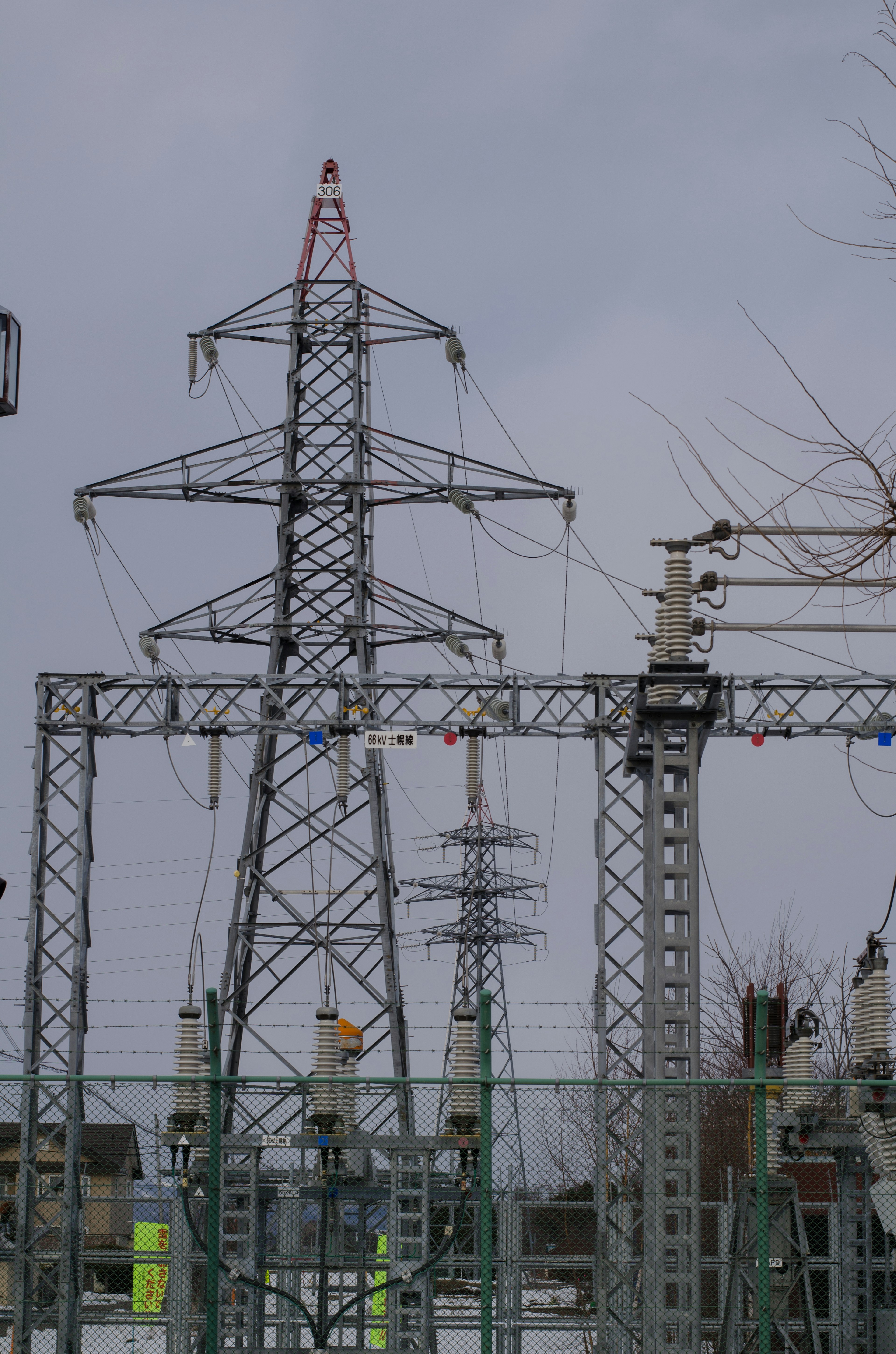 High voltage power lines and towers in a power facility under a cloudy sky