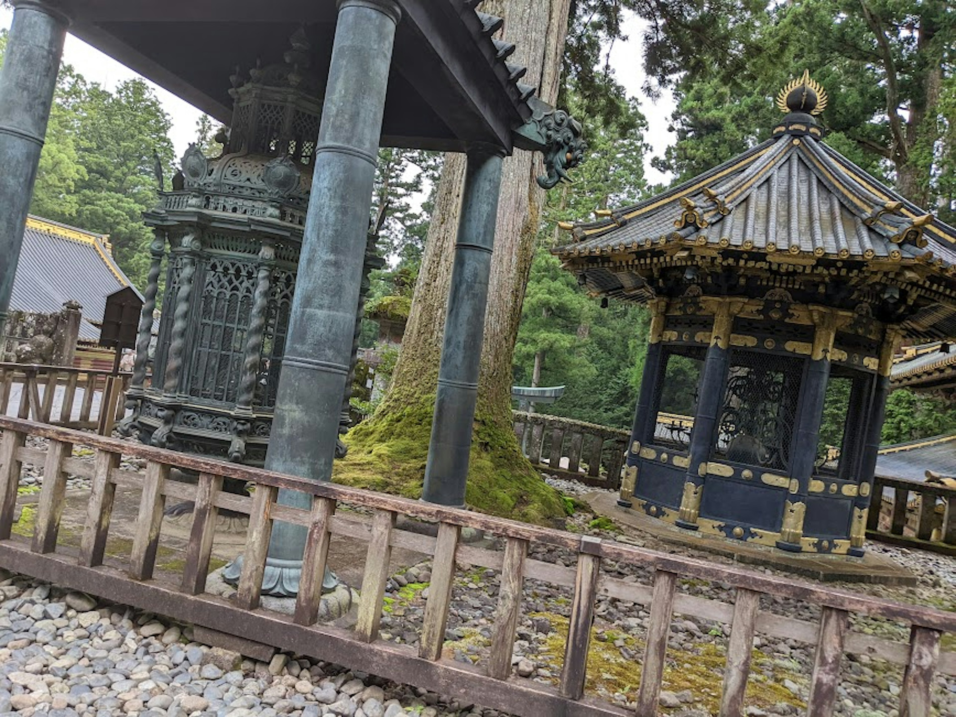 神社の伝統的な建物と石の鐘が見える風景