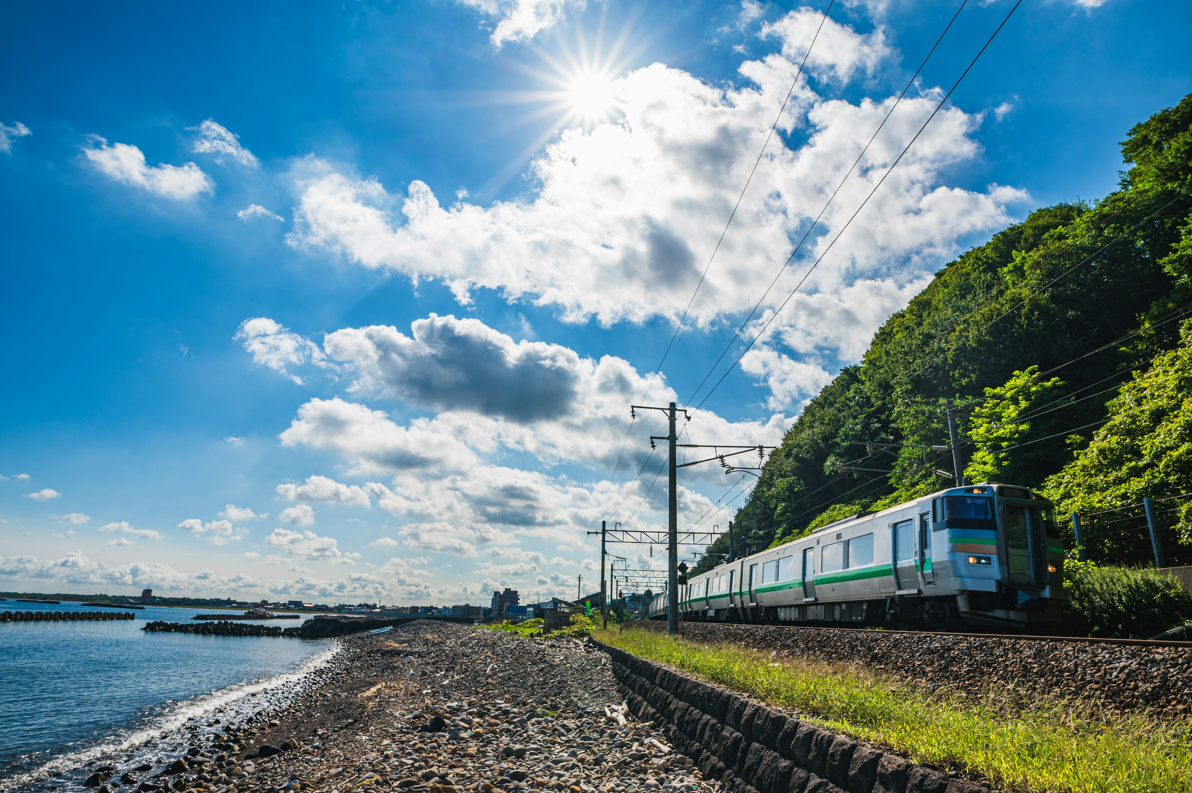 Tren que viaja a lo largo de una costa bajo un cielo azul brillante