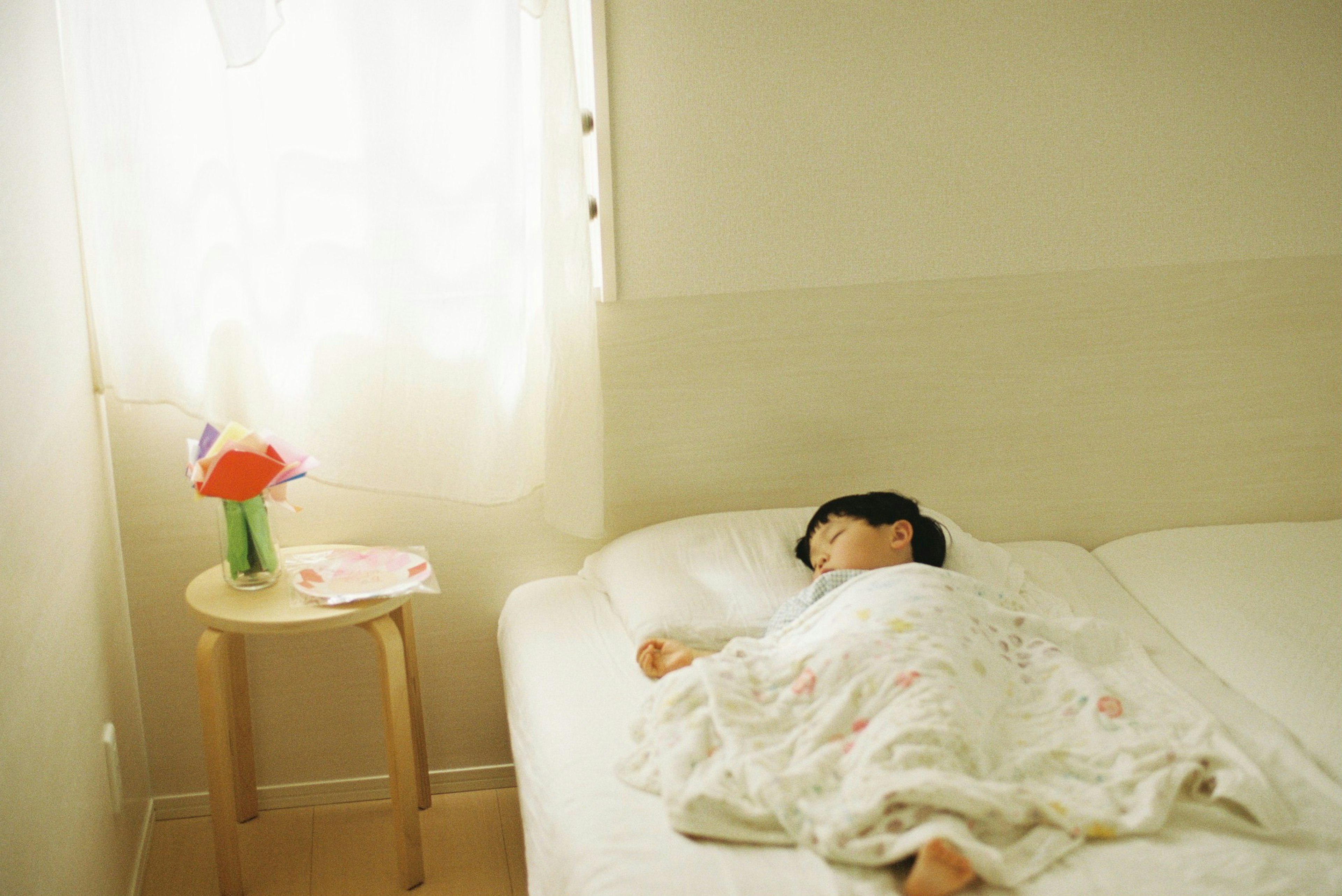 Una niña durmiendo en una cama blanca con ropa de cama suave