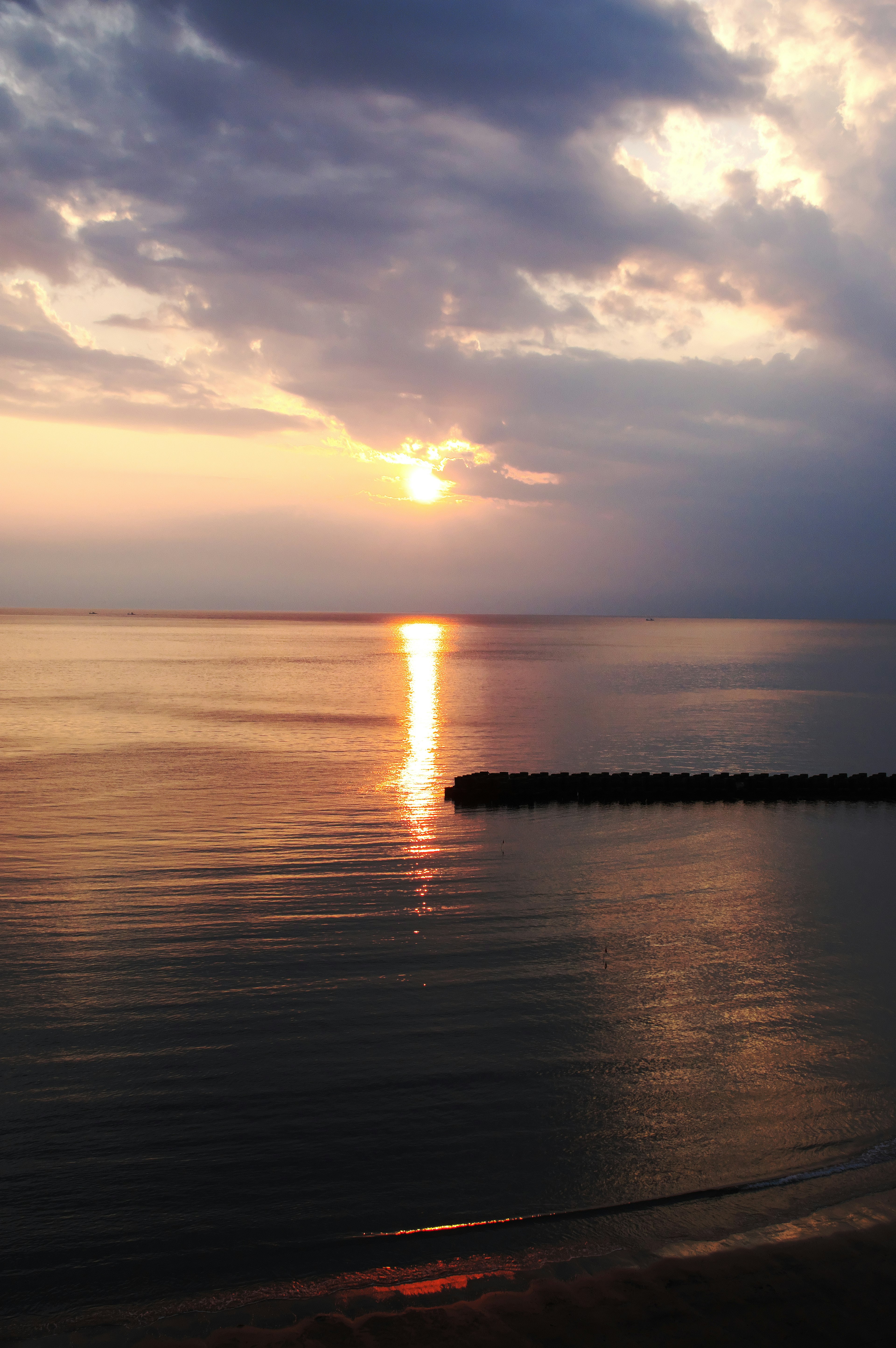 Coucher de soleil serein sur des eaux calmes avec des nuages