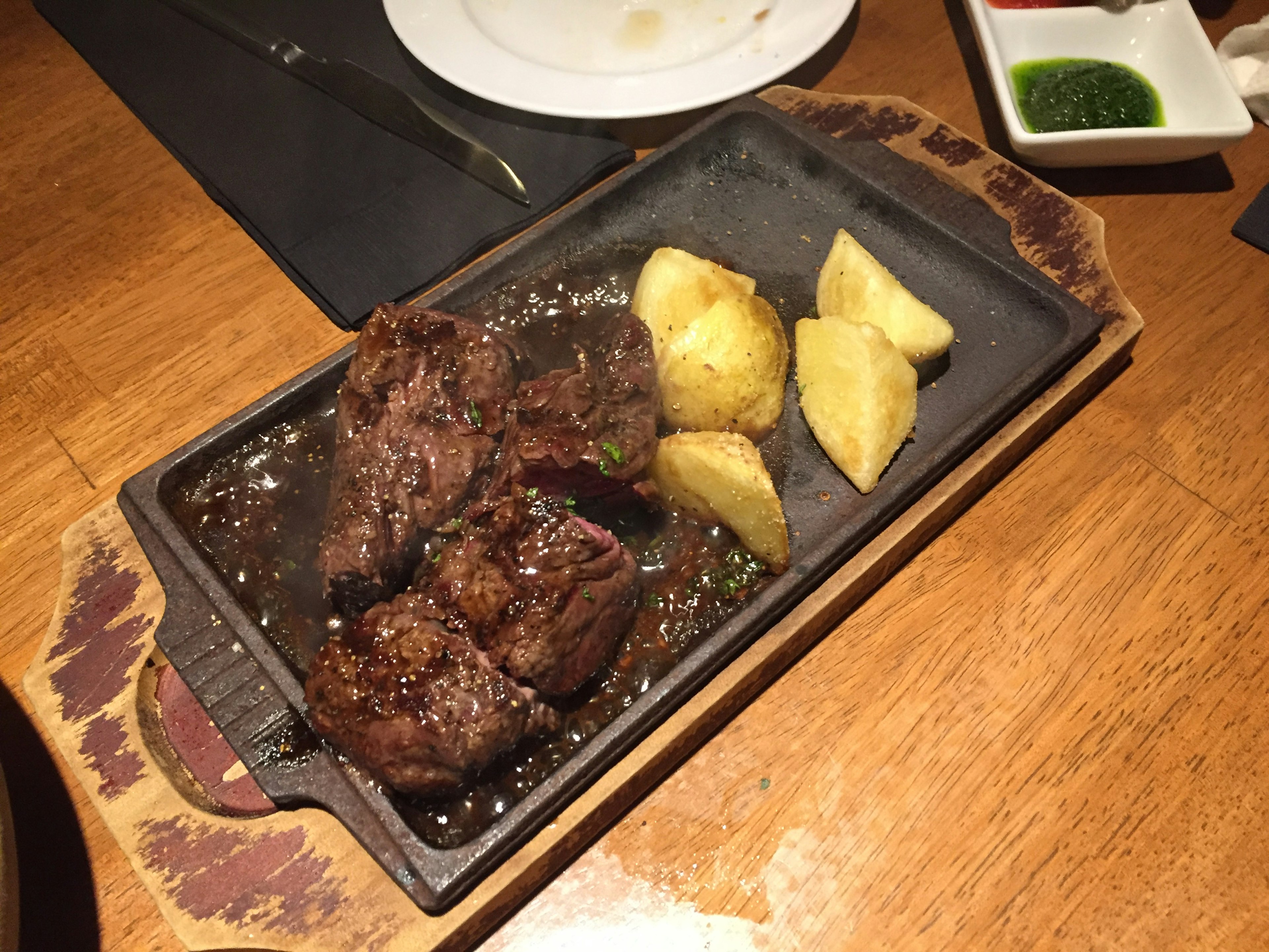 Carne a la parrilla y papas servidas en un plato caliente