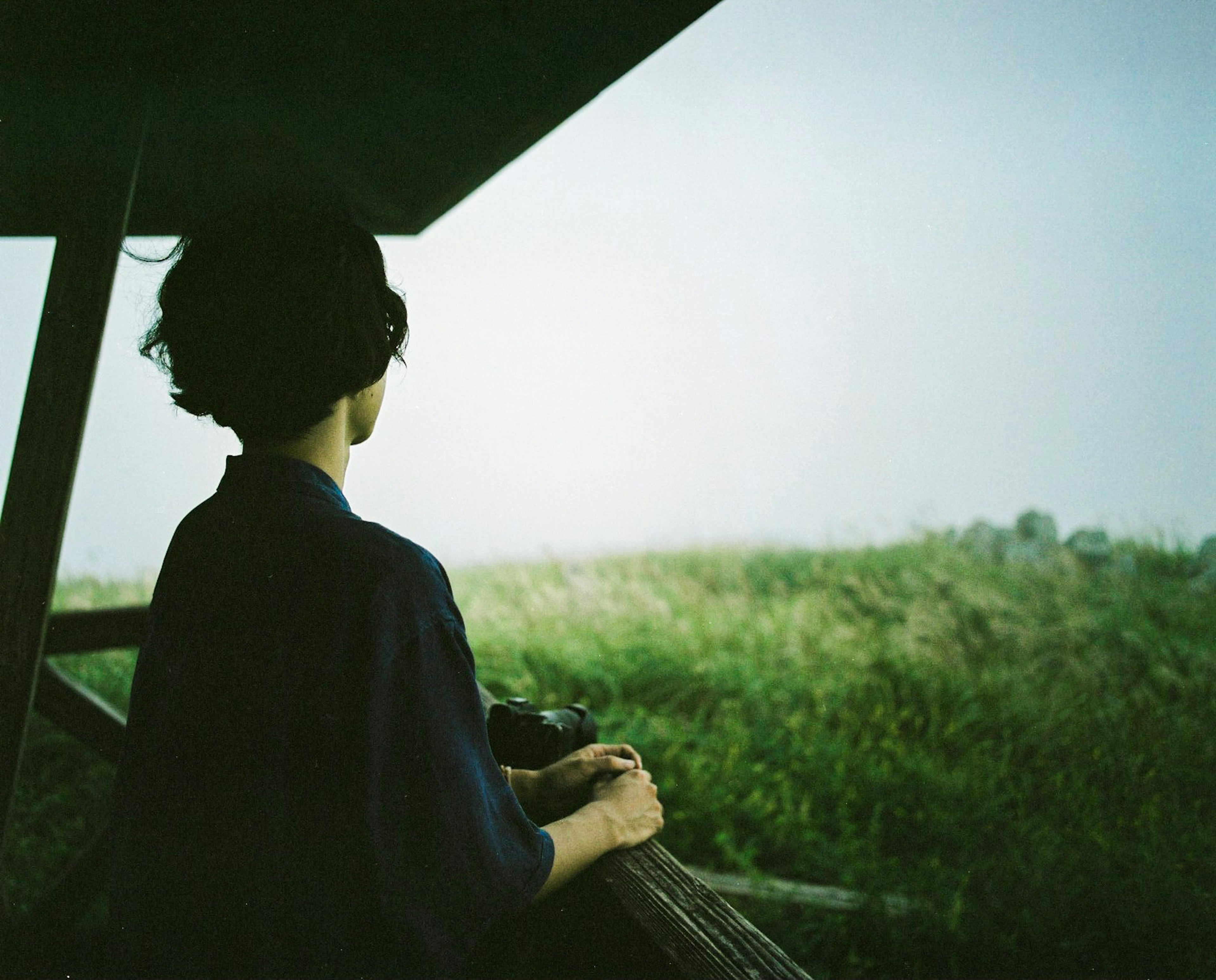 Mujer mirando un paisaje sereno desde una estructura de madera