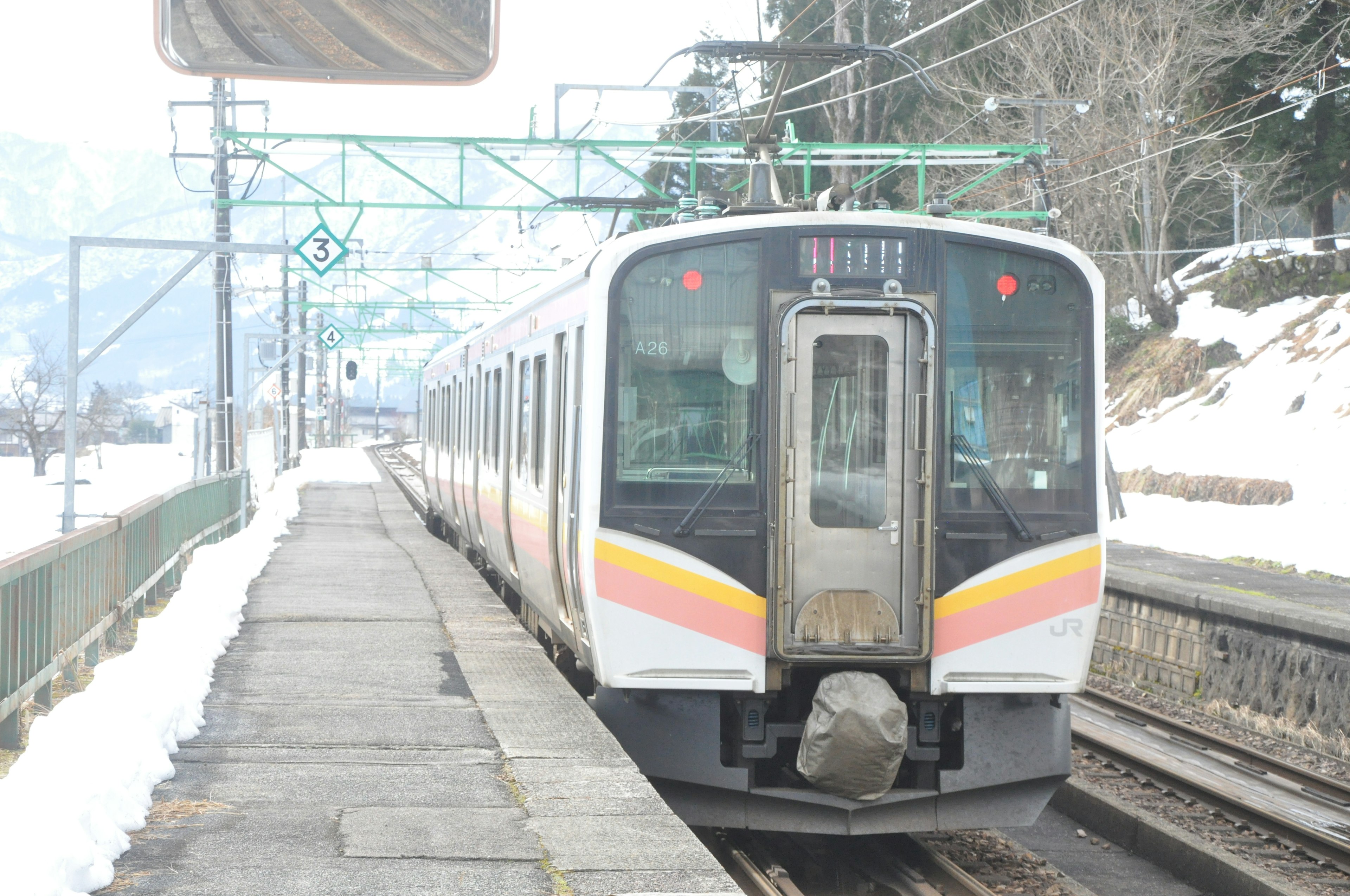 Train stopped at a snowy station with surrounding scenery