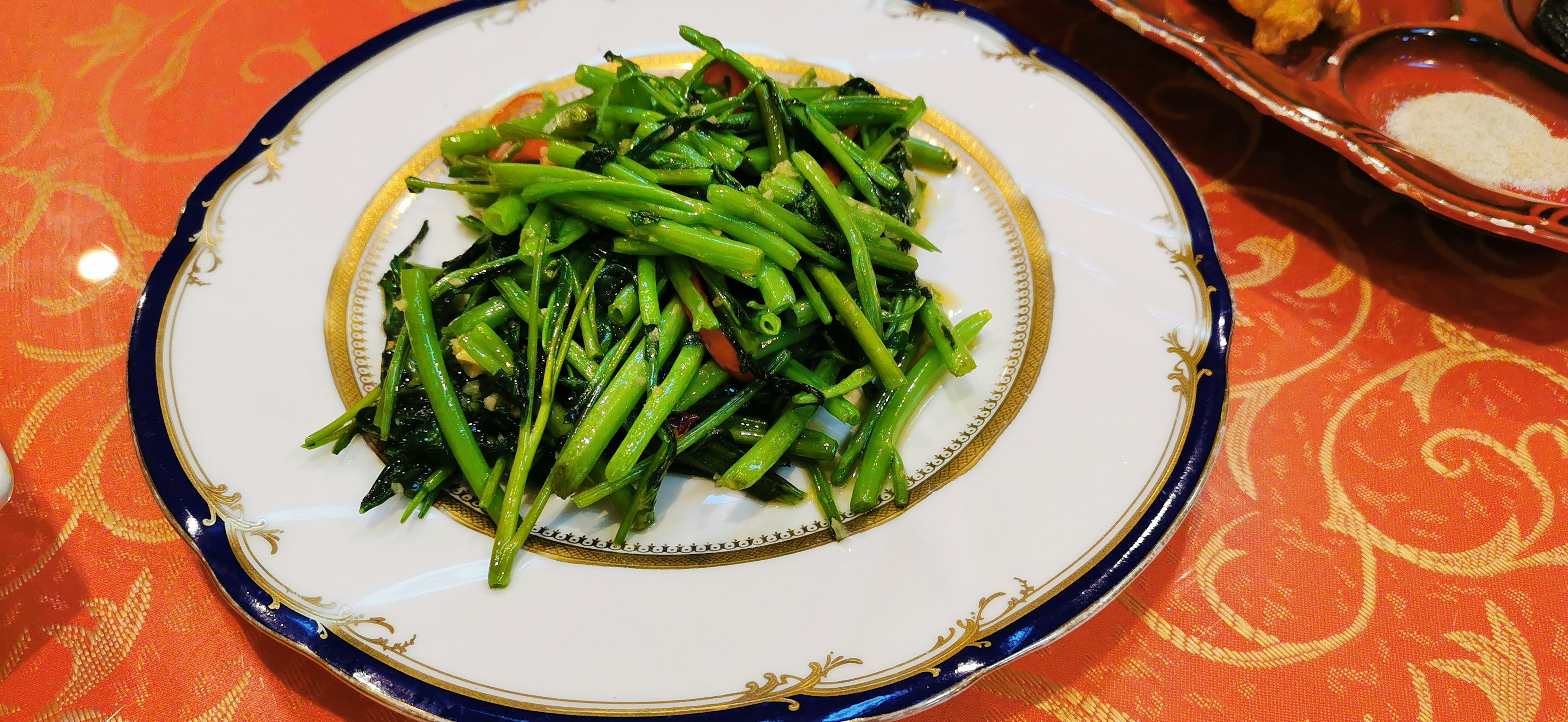 A plate of green vegetables served on a decorative white dish