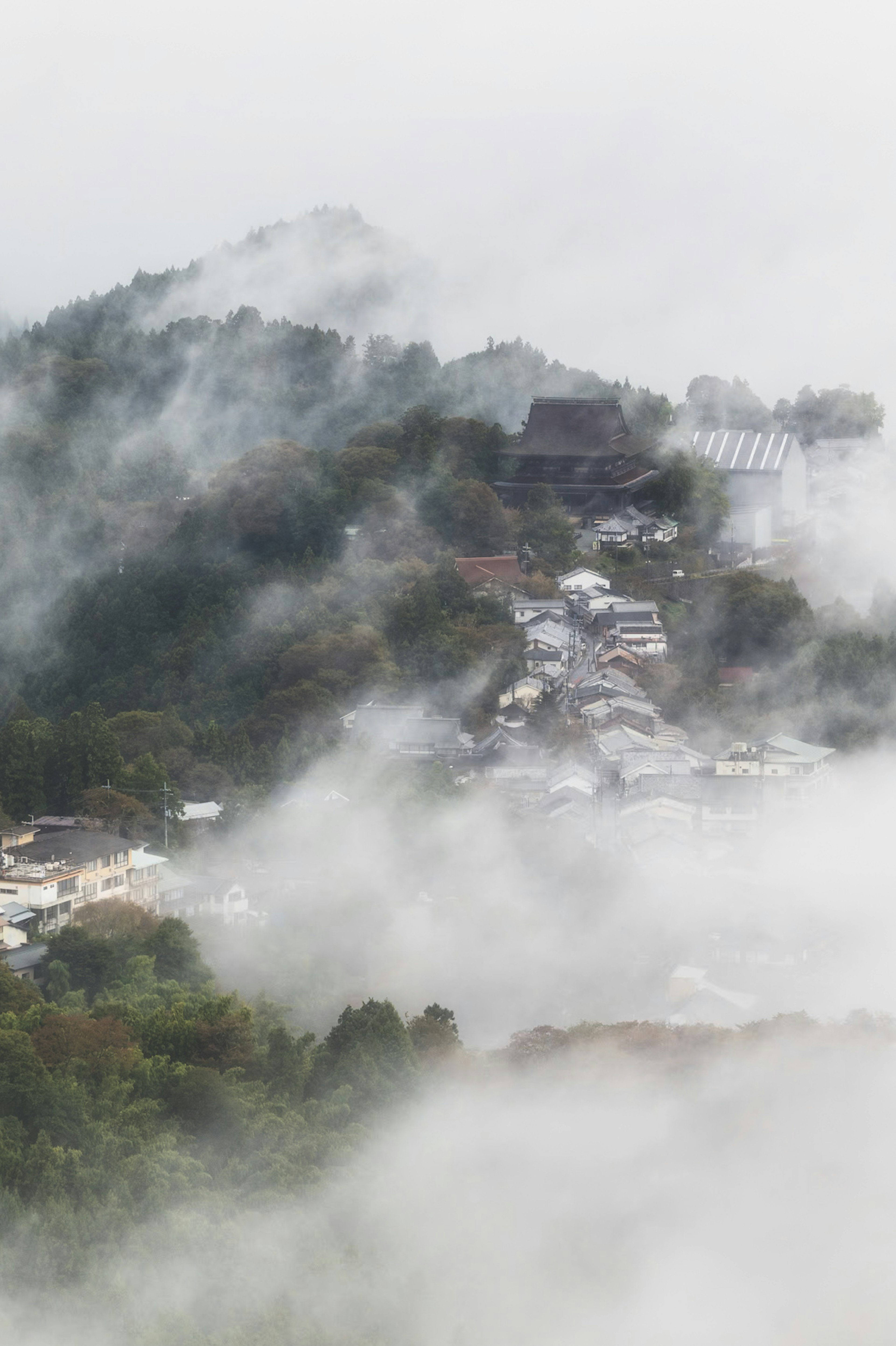 Paisaje montañoso cubierto de niebla con un pueblo