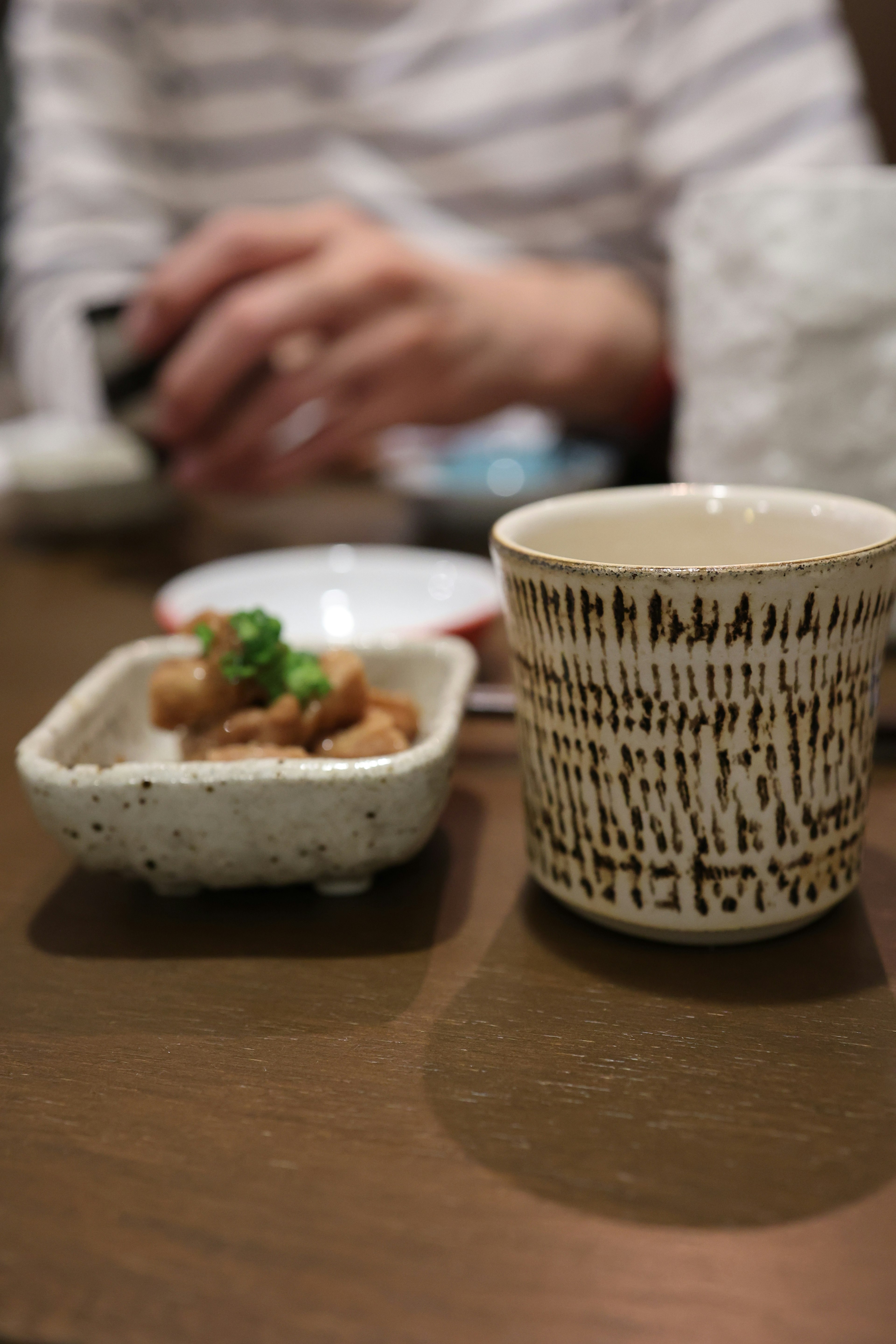 Photo of a ceramic cup and a dish of food on a table