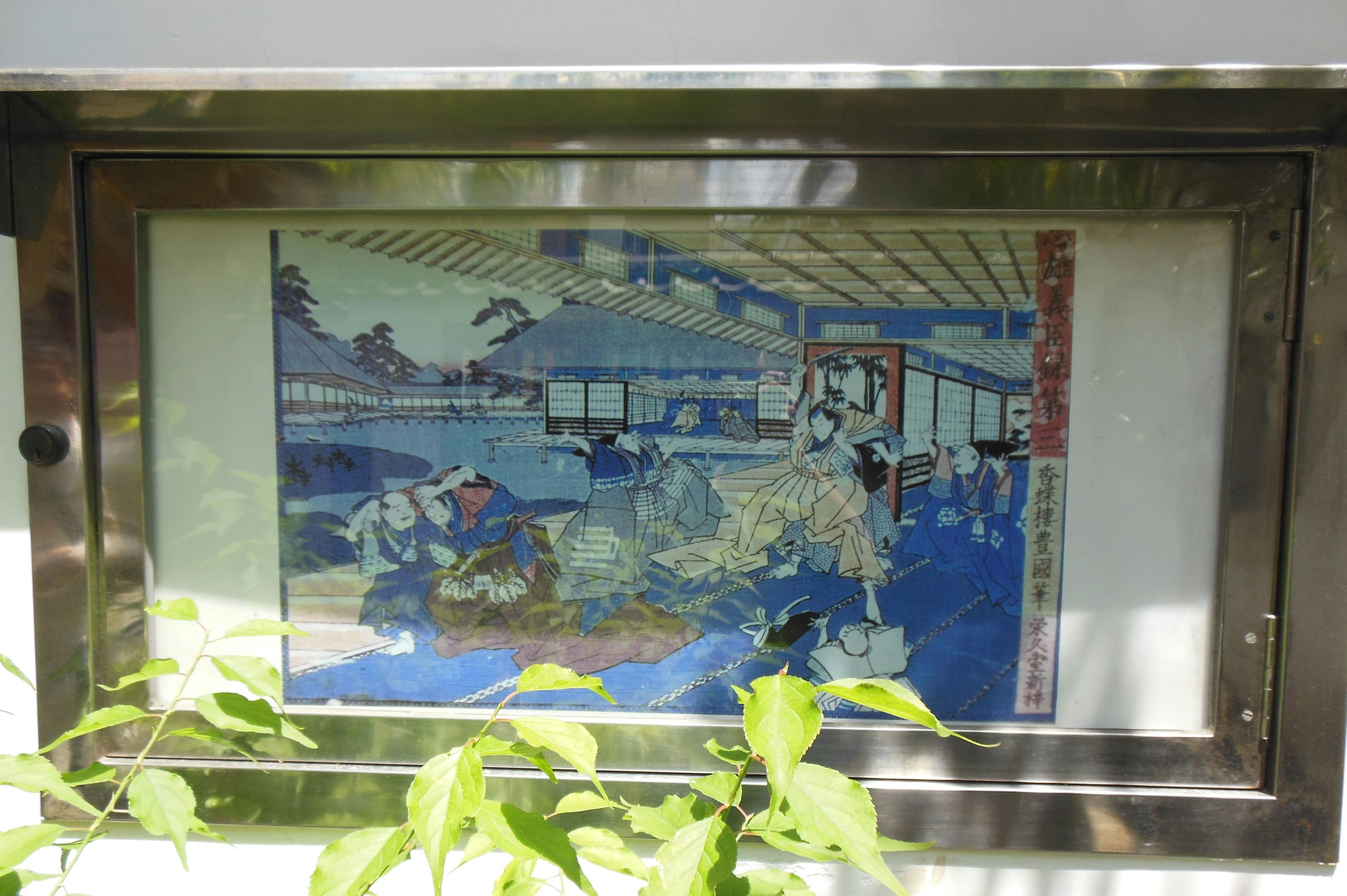 Image d'une estampe japonaise traditionnelle ukiyo-e exposée dans un cadre en verre avec de la verdure