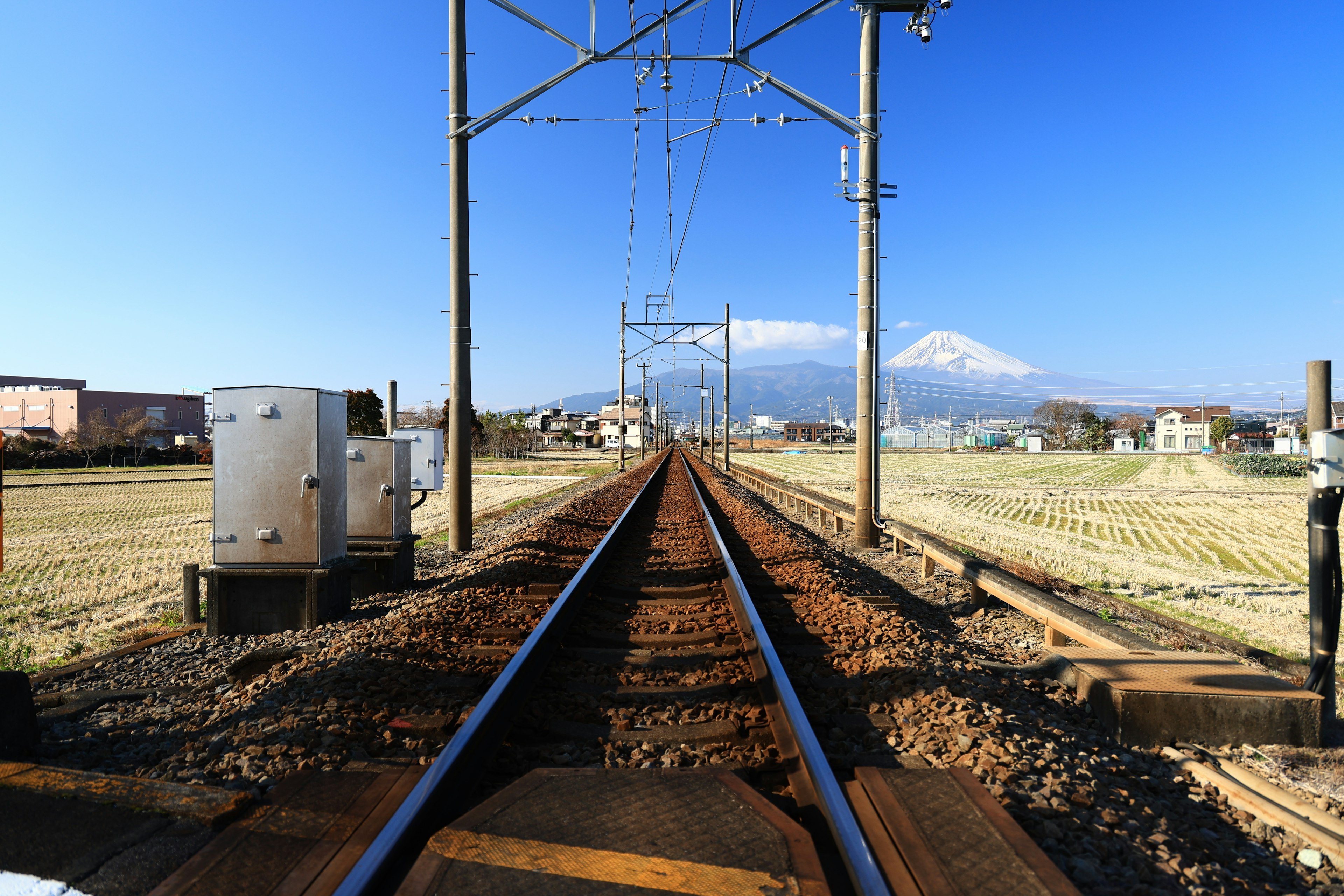 鉄道の線路が続き、遠くに雪をかぶった山が見える風景