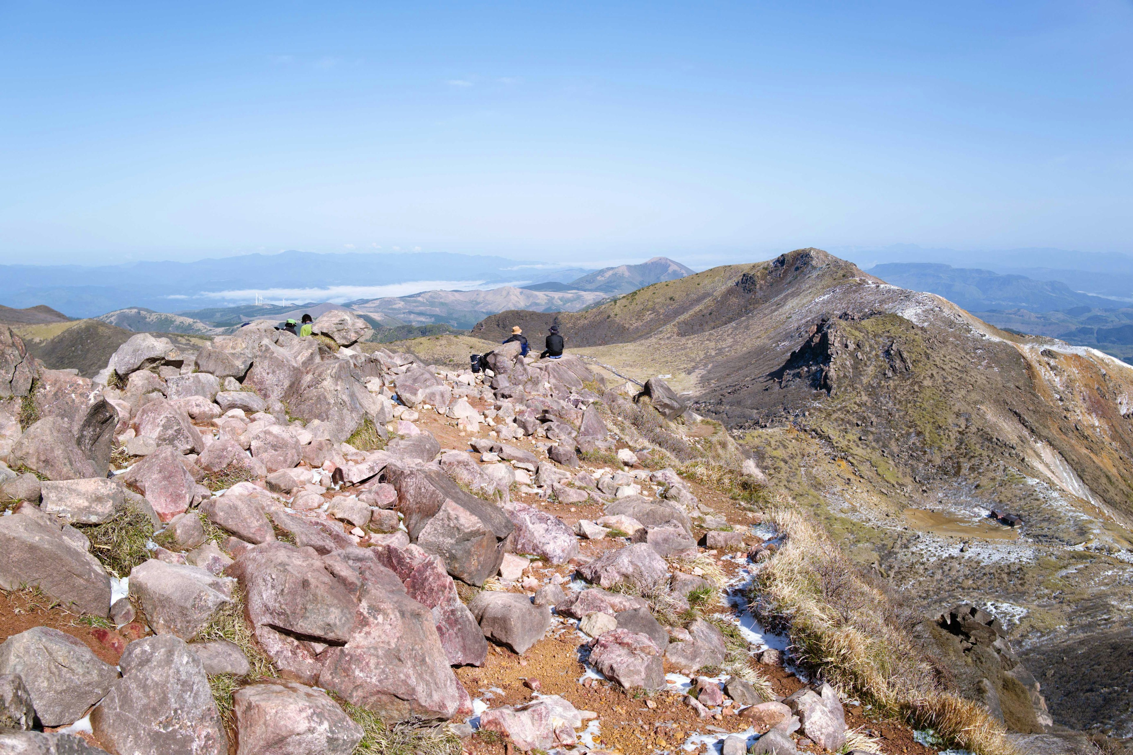 Vue panoramique depuis un sommet de montagne avec un terrain rocheux et des collines vertes