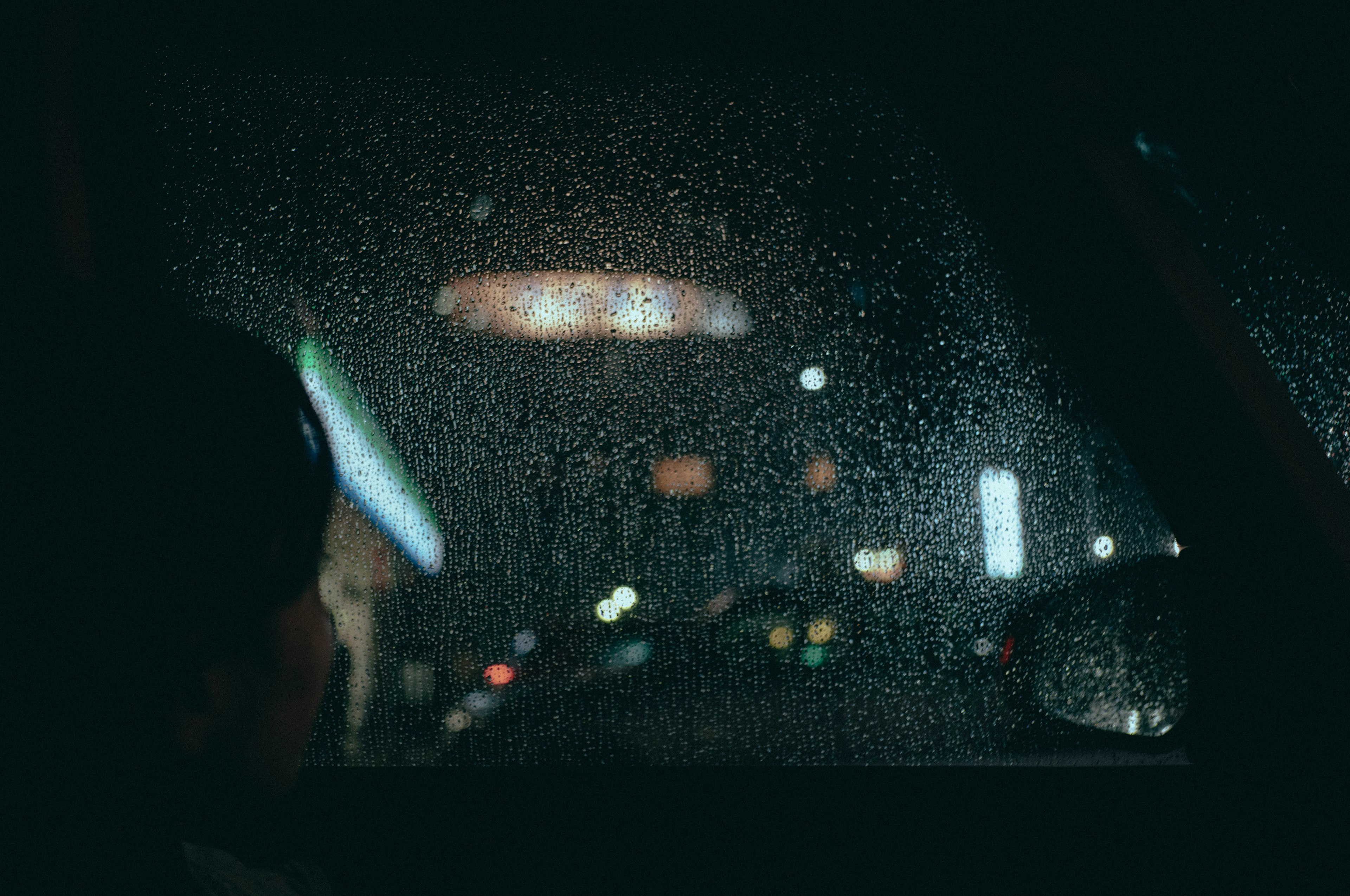 Paysage urbain nocturne vu à travers une fenêtre humide avec le profil d'un enfant