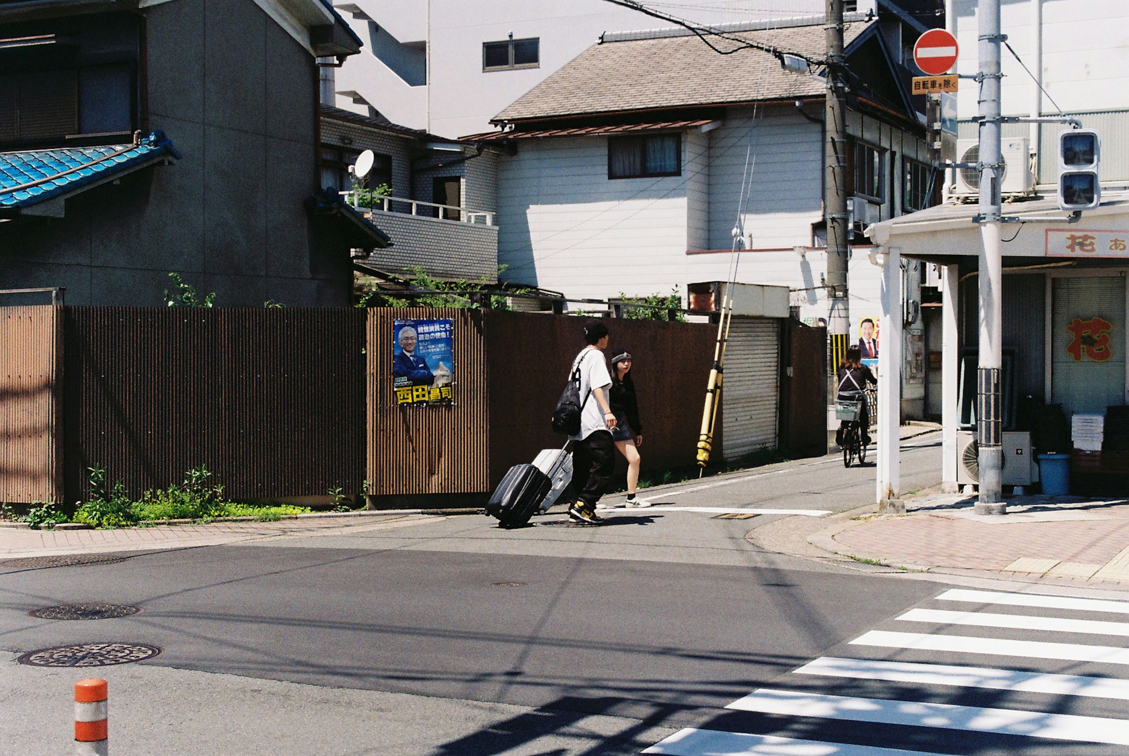 旅行者がスーツケースを引いて横断歩道を渡る風景