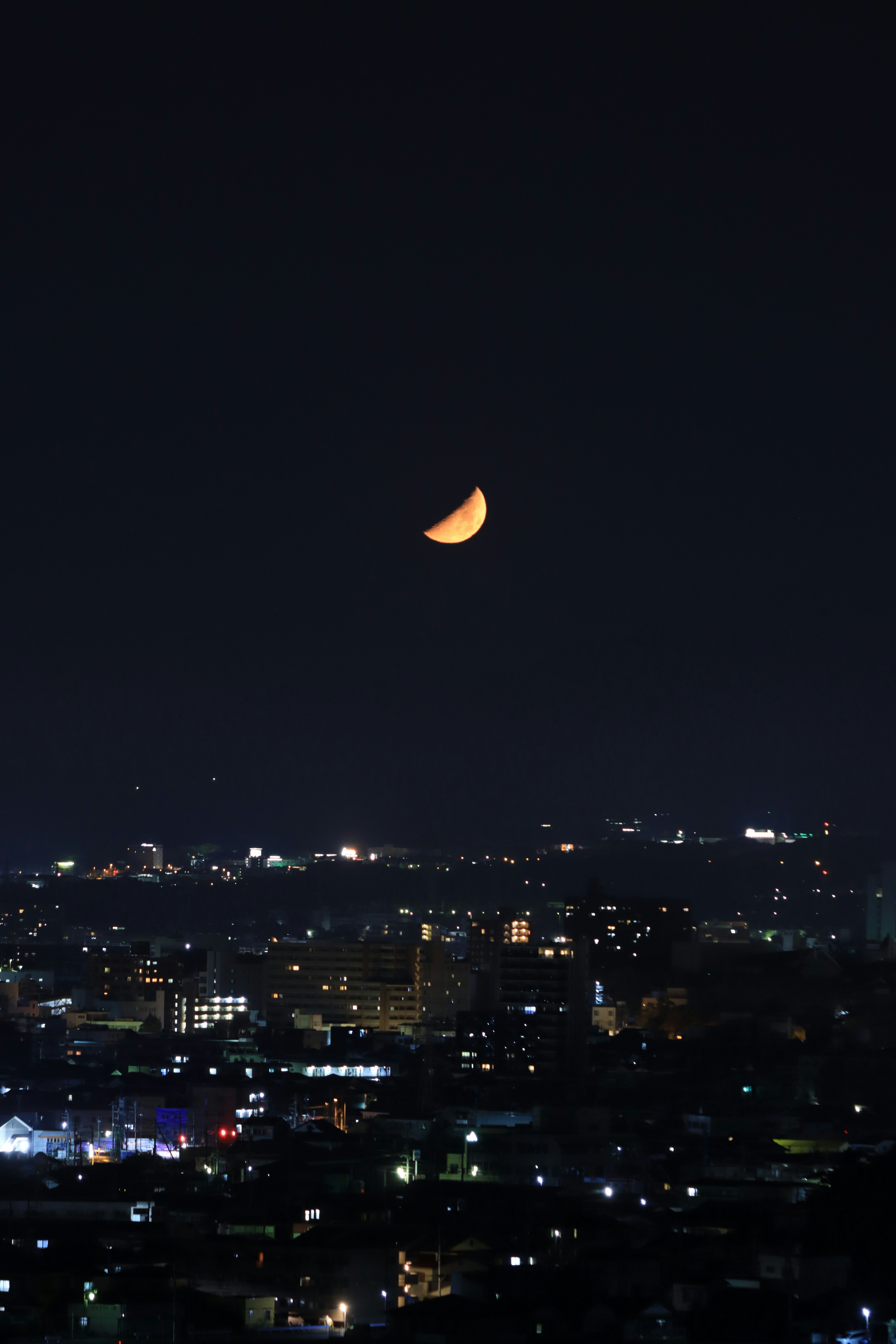 Cielo nocturno con una luna creciente sobre el horizonte de la ciudad