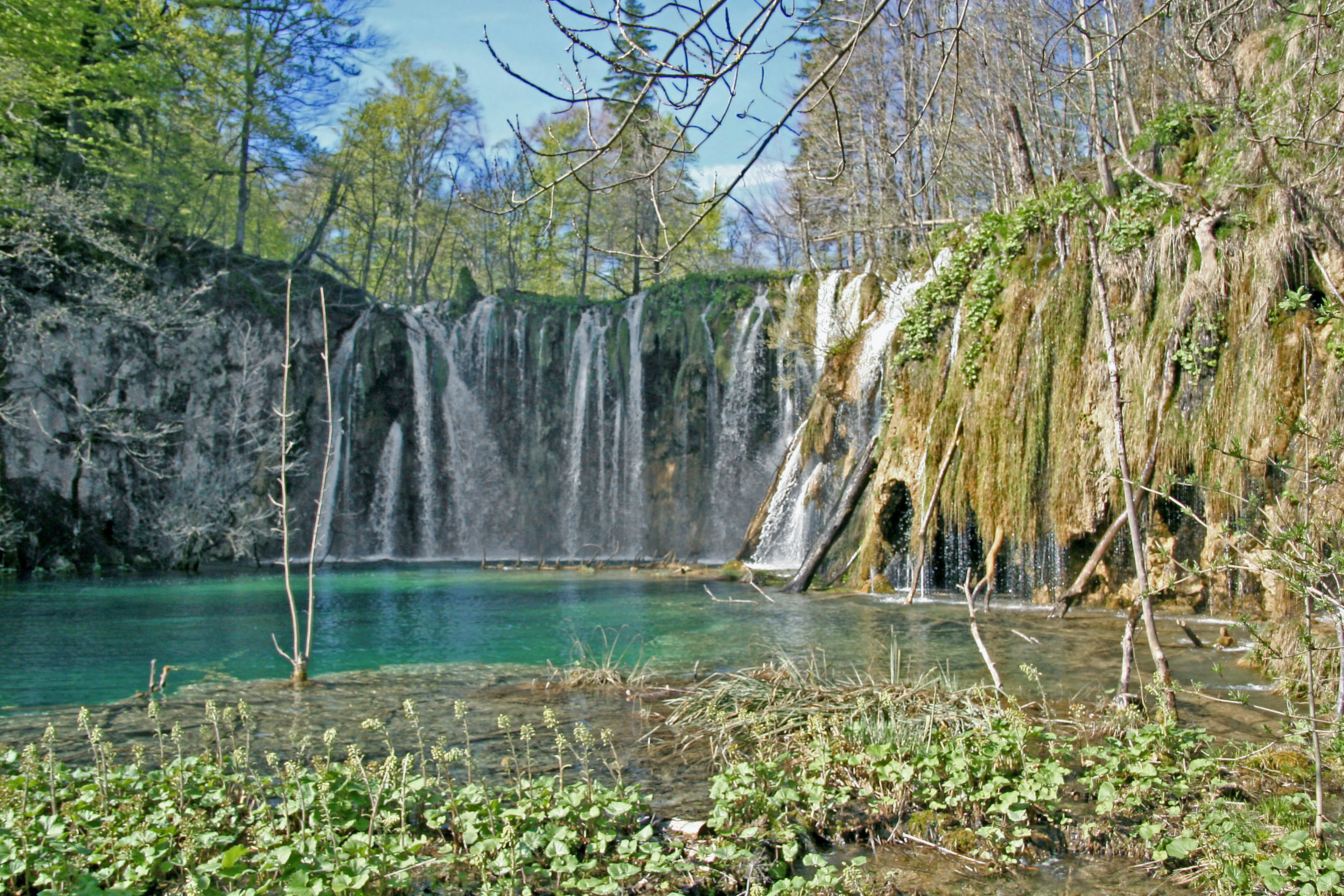 Natural landscape featuring a blue pond and cascading waterfall